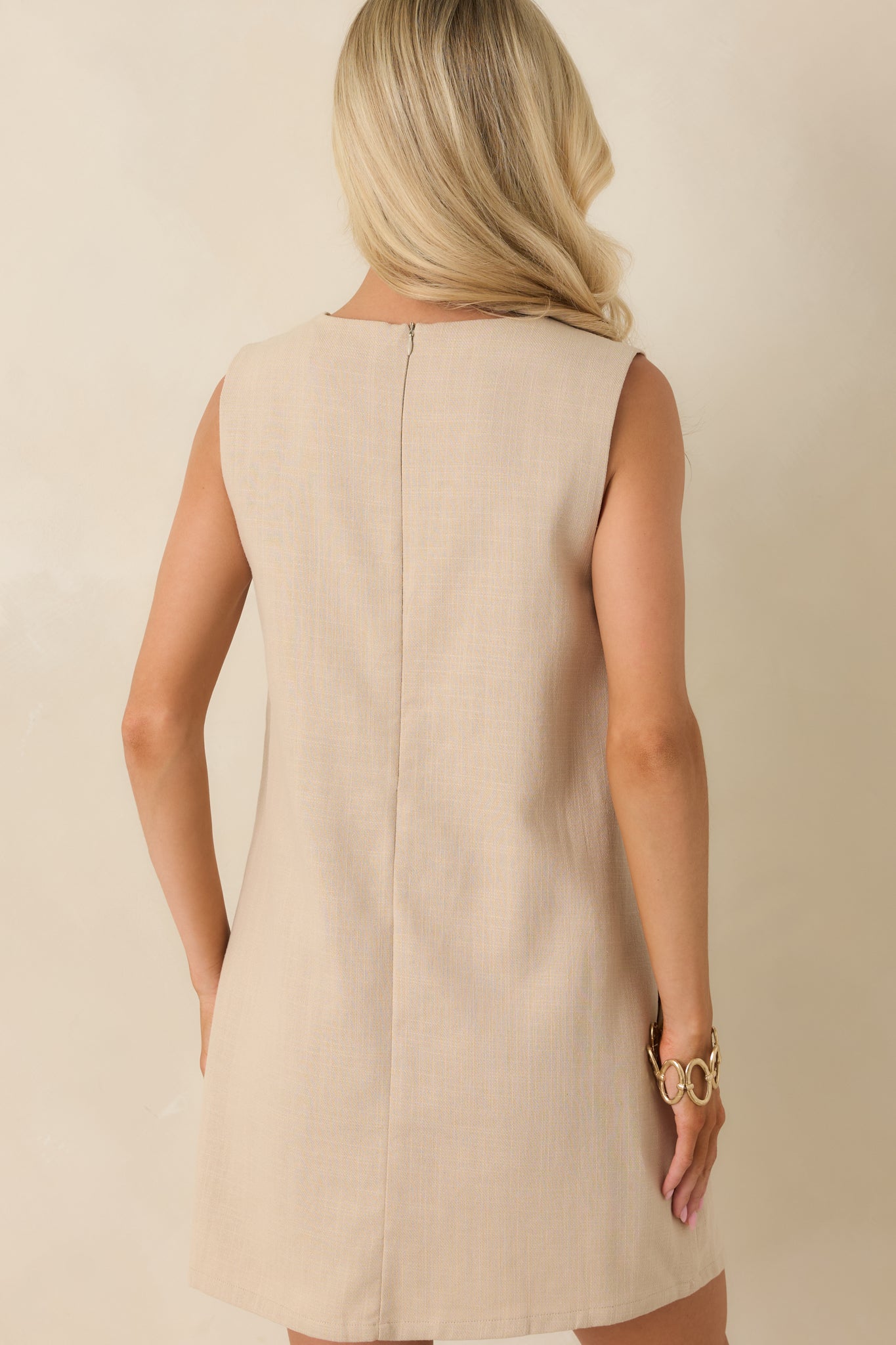Back view of the sleeveless cotton mini dress highlighting the concealed back zipper closure and clean shift silhouette.