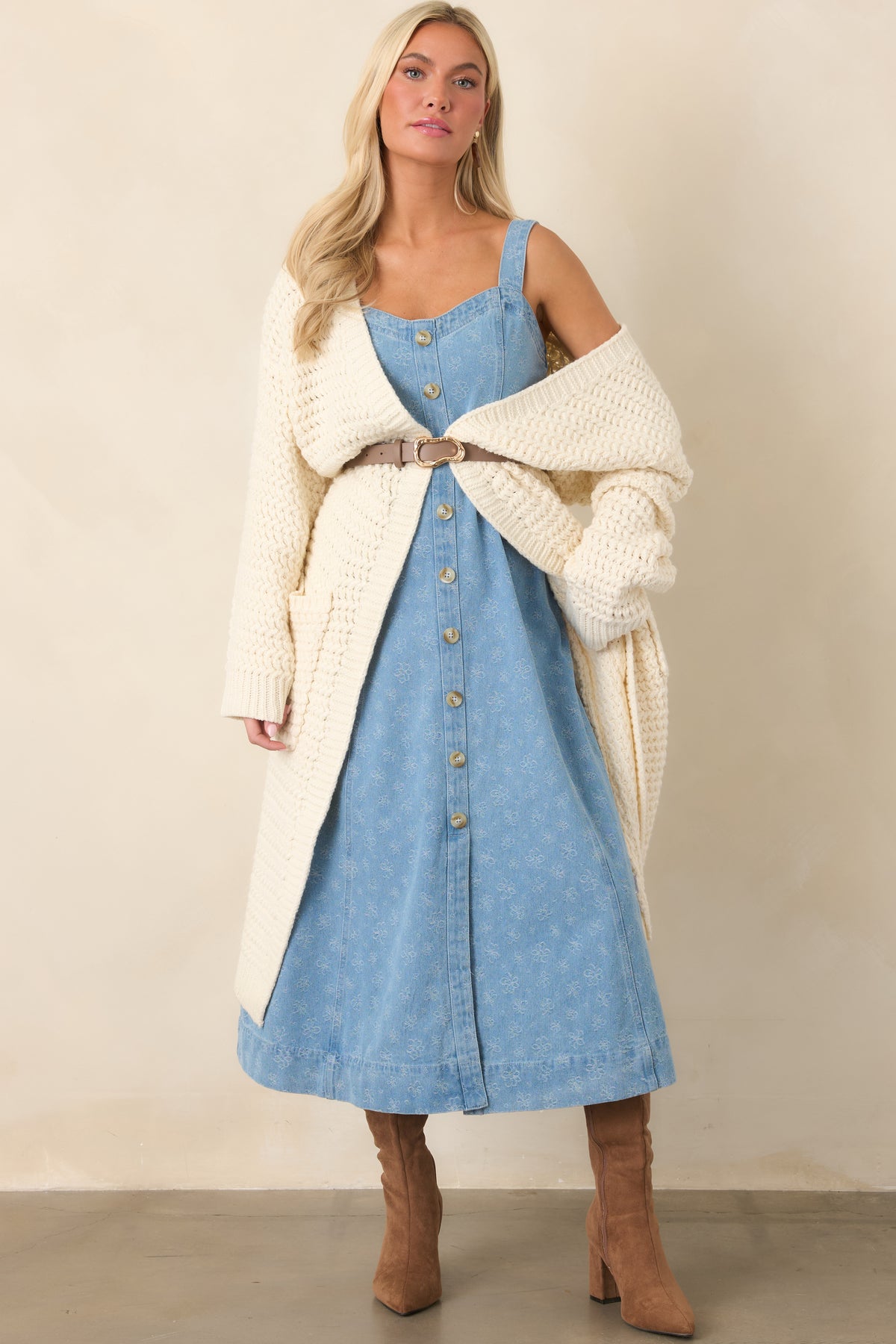 Sleeveless denim dress highlighting decorative front button detailing and a softly flared A-line silhouette.