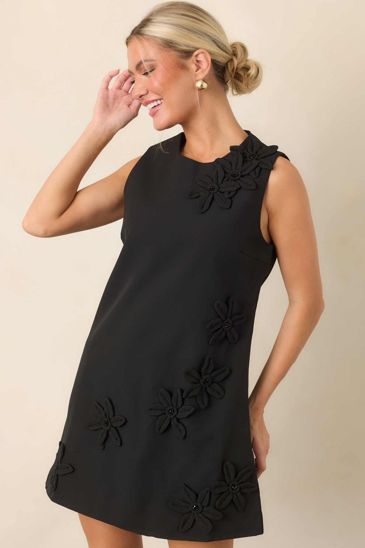 Close view of the sleeveless dress showcasing dimensional floral appliqués with glossy black beaded centers.