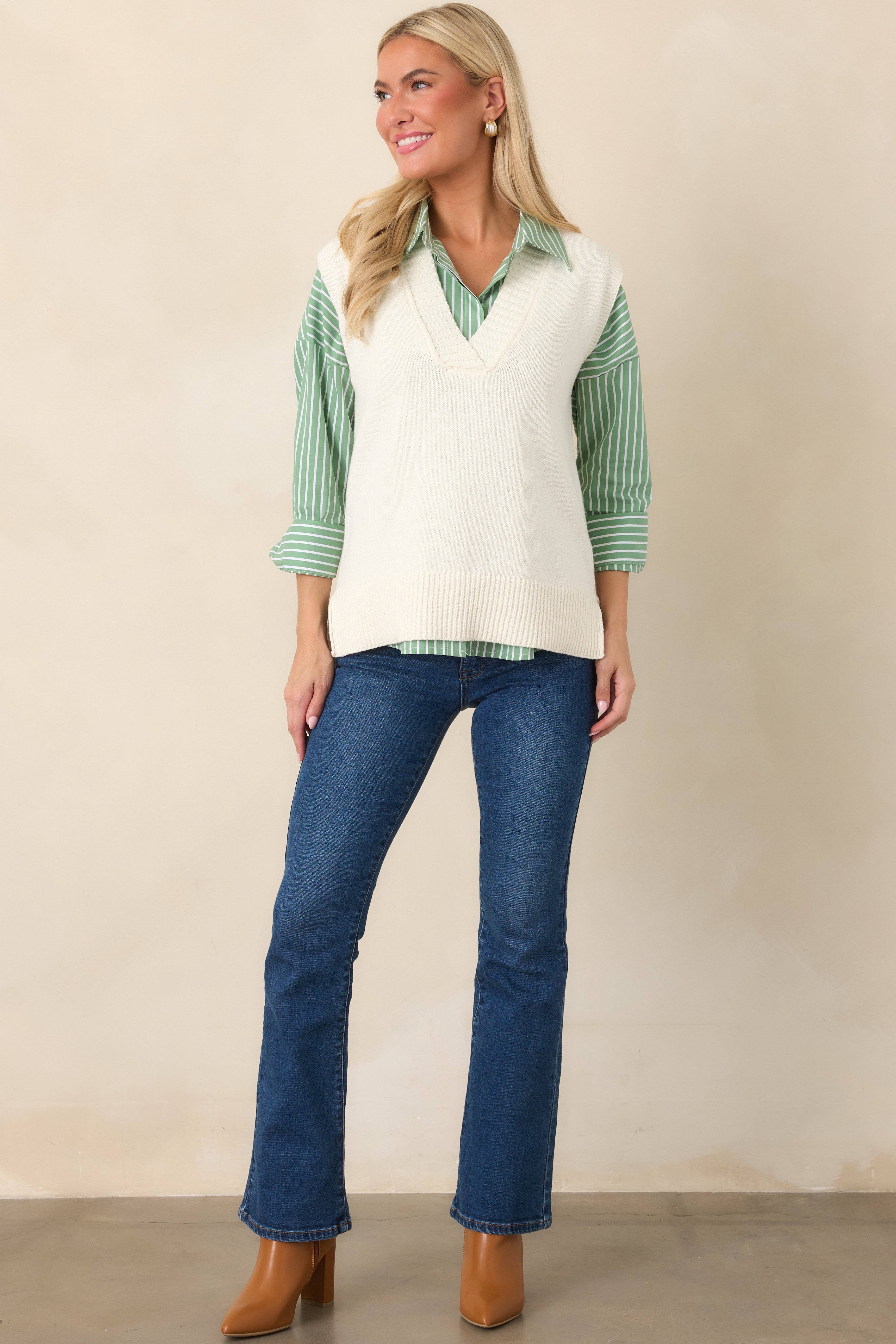 Sleeveless ivory knit vest showcasing a refined shape, textured ribbed neckline, and wide ribbed hem with a comfortable layered look.