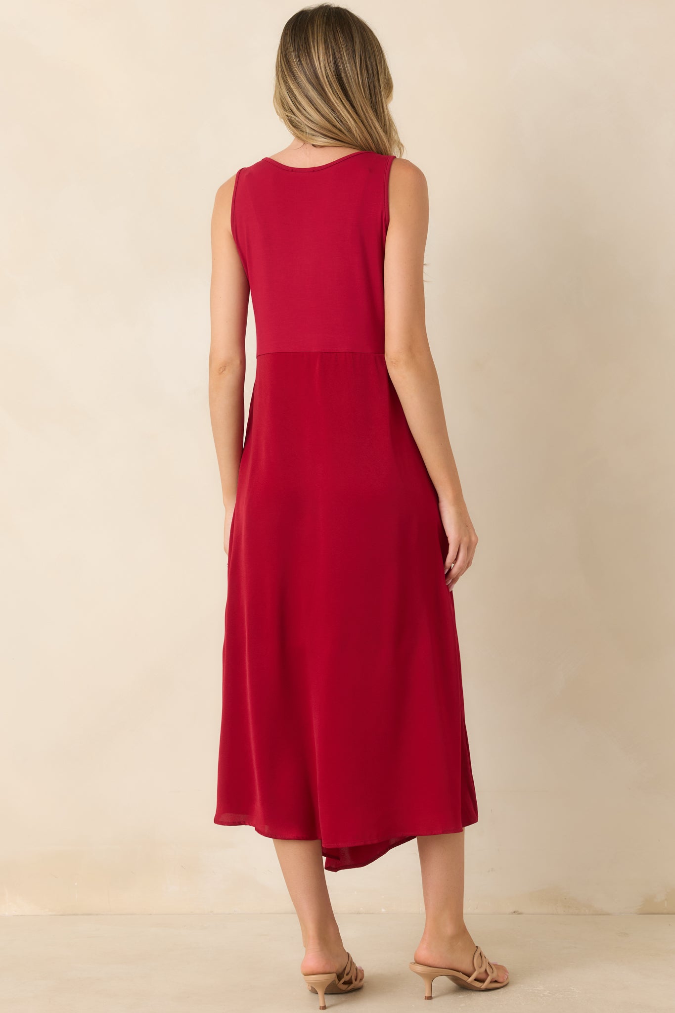 Rear view of the sleeveless midi dress featuring a smooth knit bodice and a flowing satin skirt.