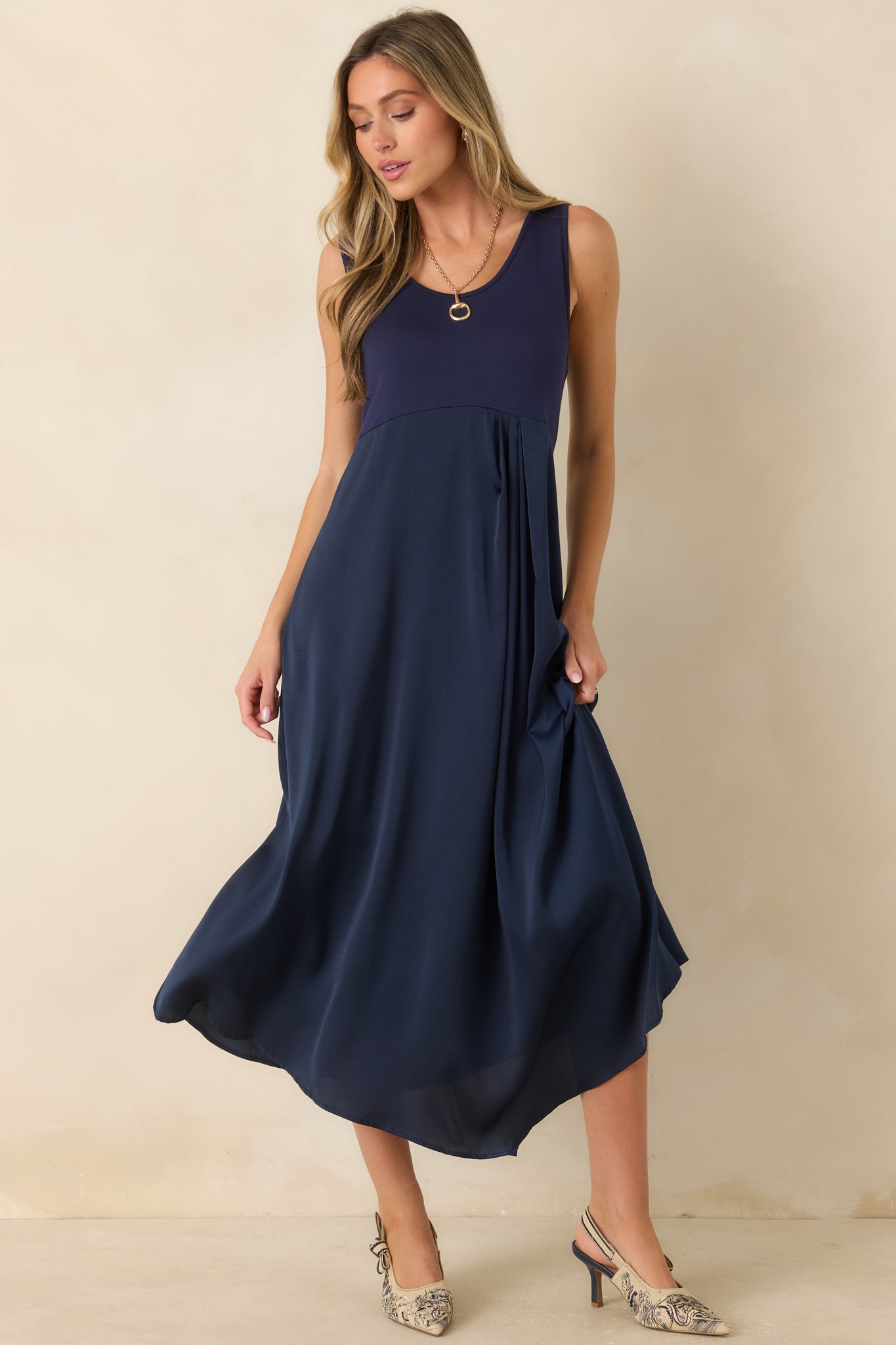 Sleeveless midi dress featuring a stretch-knit bodice, scoop neckline, flowing satin skirt, and elegant mixed-fabric design.