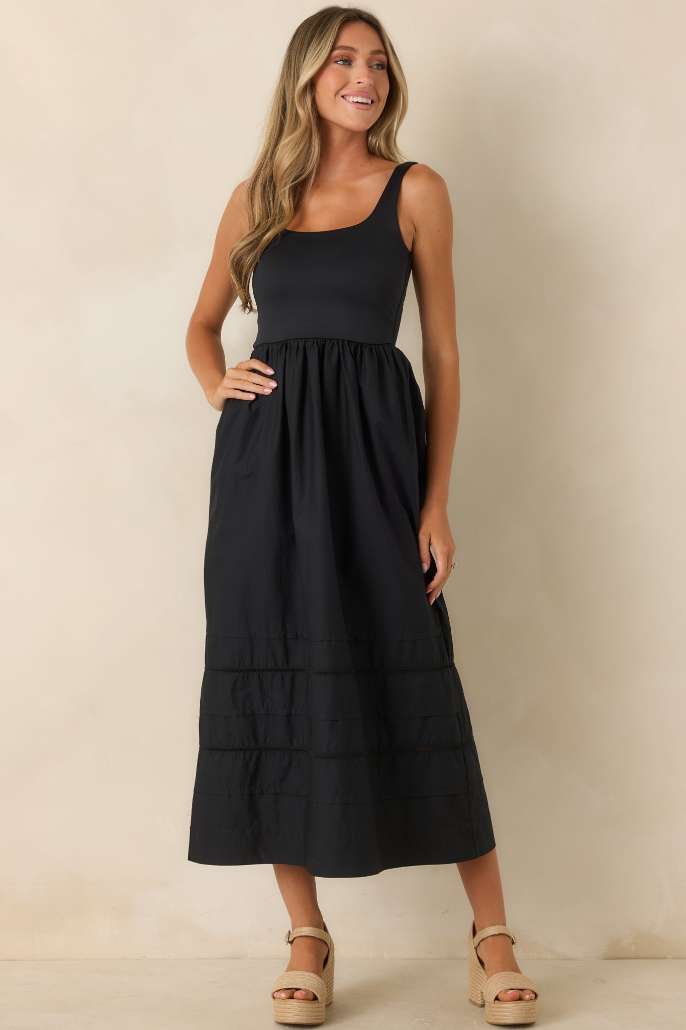 Sleeveless midi dress featuring a fitted bodice, scoop neckline, and flowing gathered skirt.