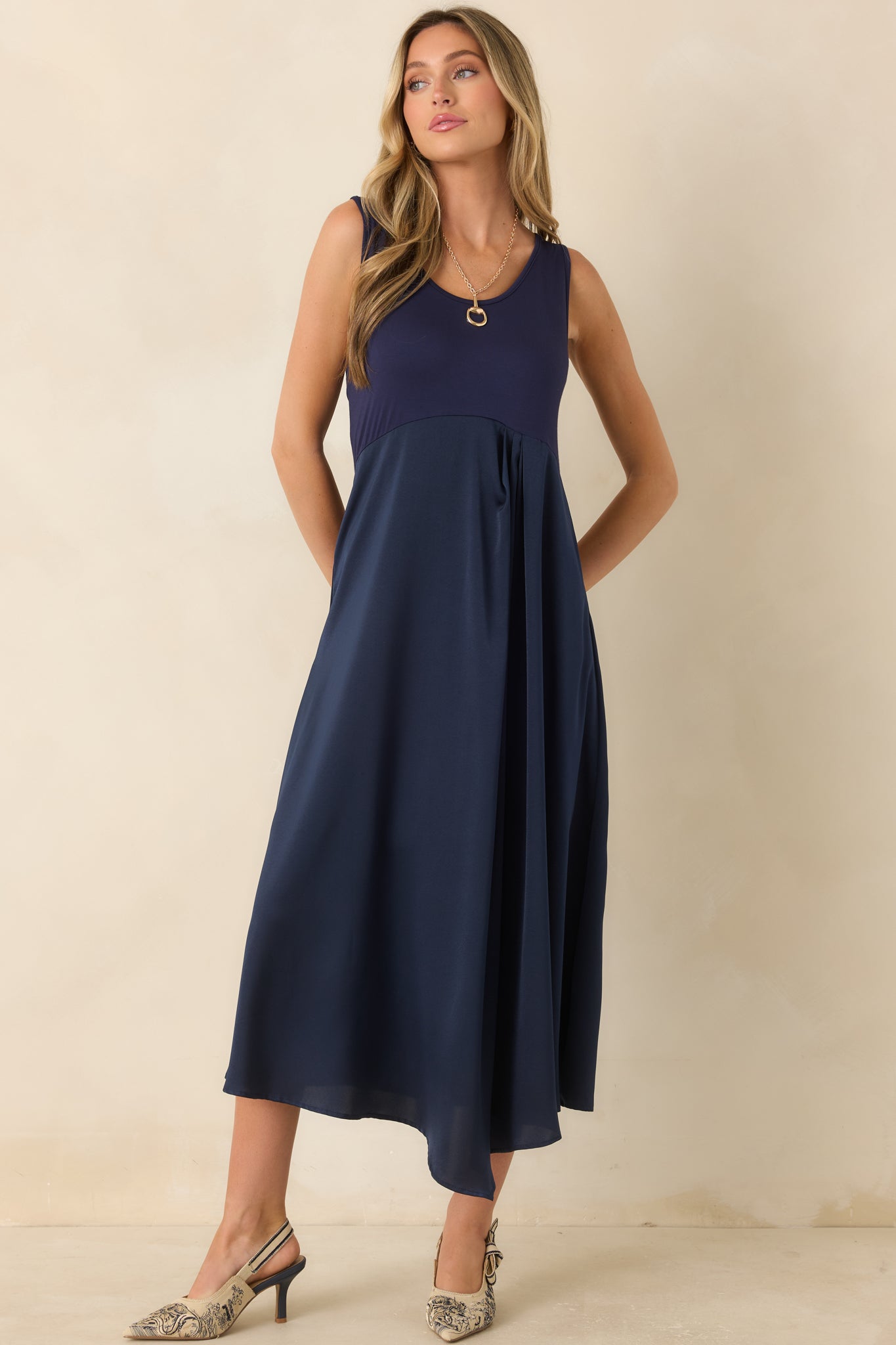 Sleeveless mixed-fabric midi dress combining a comfortable knit bodice with a lustrous satin skirt and an easy flowing silhouette.