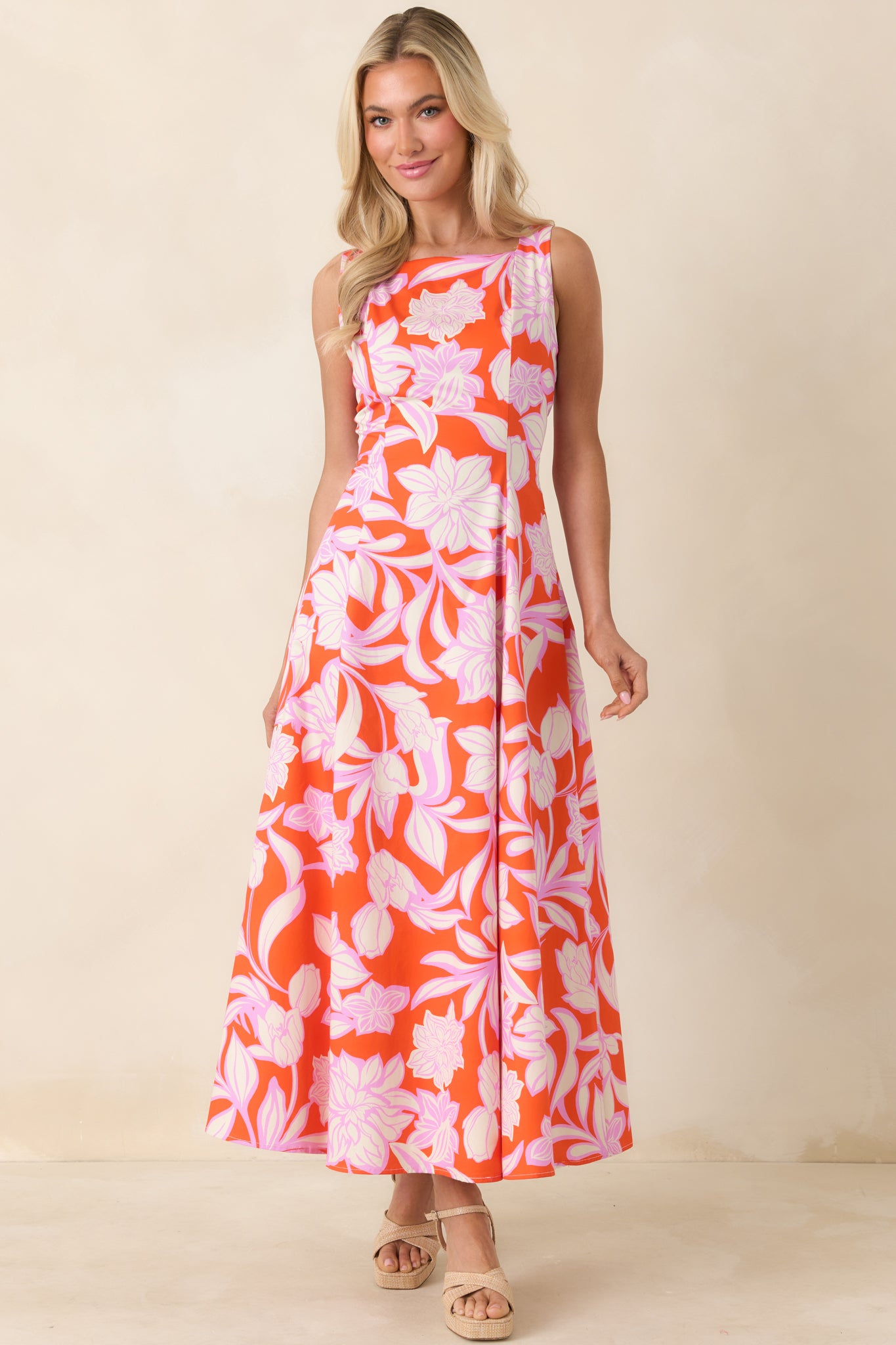 Sleeveless orange maxi dress with orchid pink floral print and fluid silhouette.