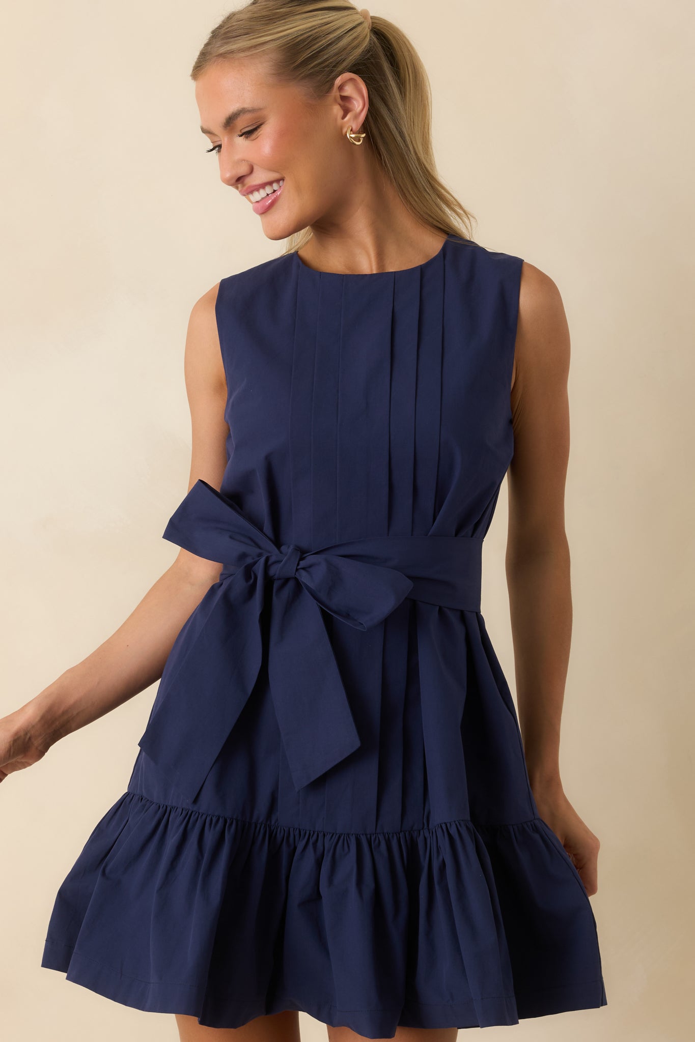 Sleeveless fit-and-flare mini dress showcasing a round neckline, structured pleated bodice, and statement waist bow.