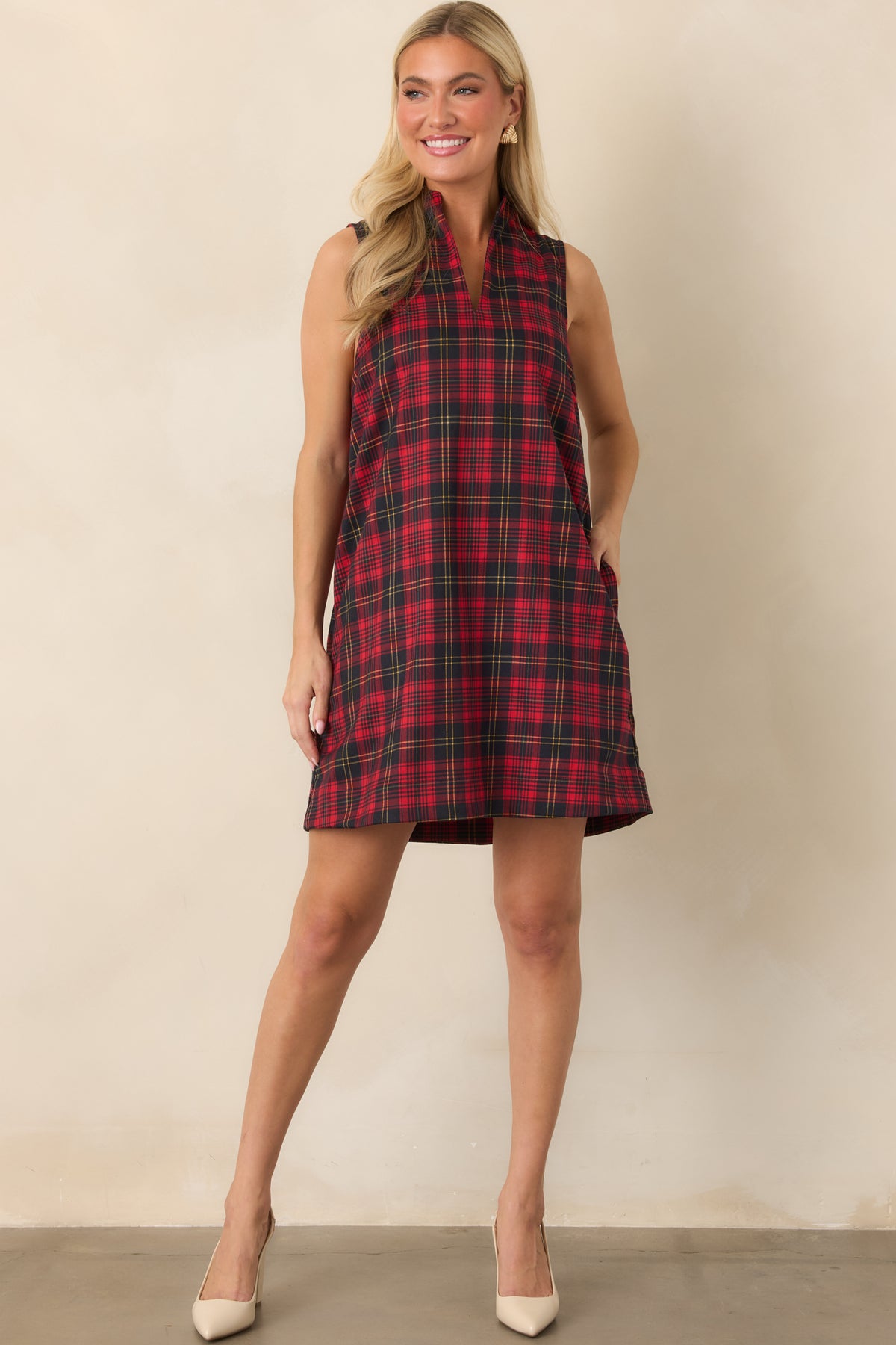 Sleeveless red and black plaid mini dress featuring a relaxed shift shape, contrasting lines, and practical side pockets.