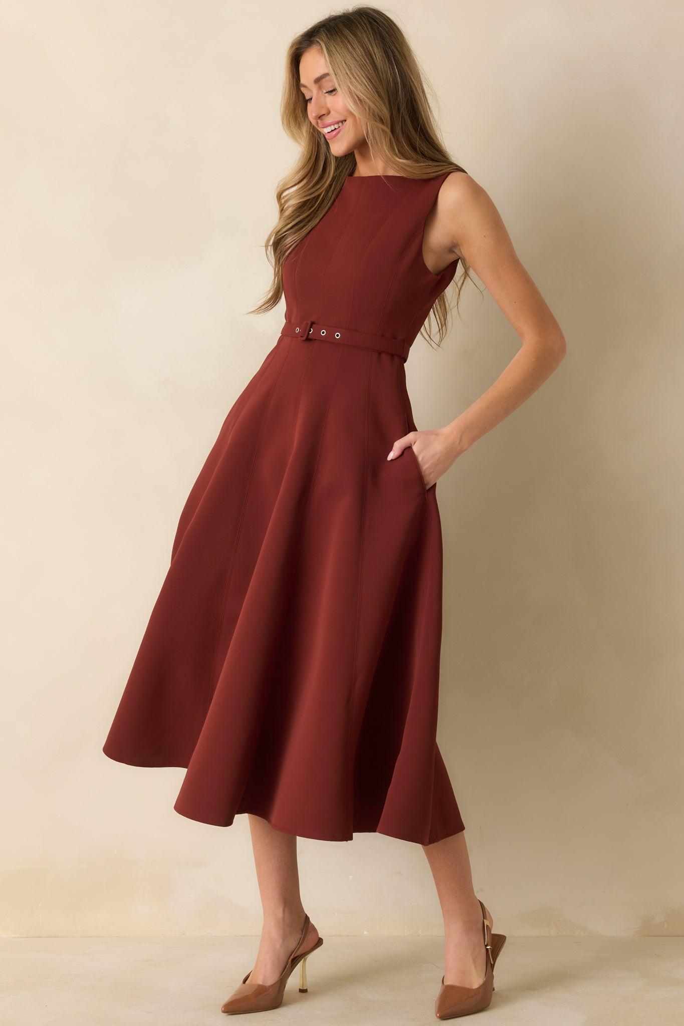 Sleeveless red midi dress featuring a cinched waist with adjustable belt and graceful skirt flare.
