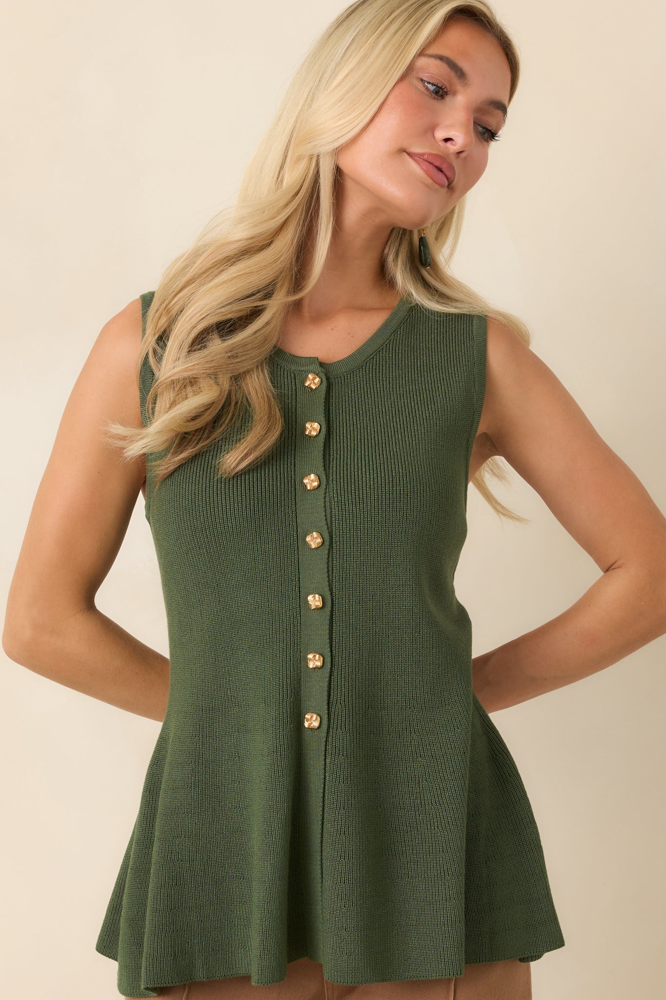 Sleeveless top with a soft knit texture, structured shape, and feminine peplum finish.