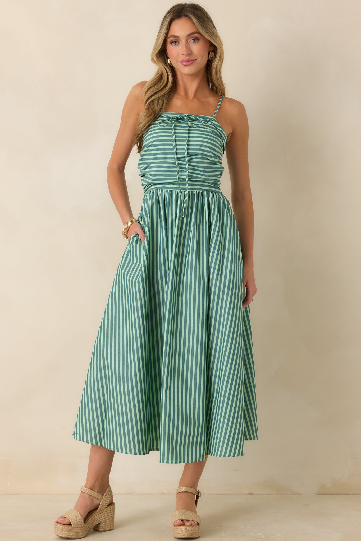 Sleeveless striped maxi dress featuring a softly ruched bodice, adjustable shoulder straps, and a full skirt designed for graceful movement.