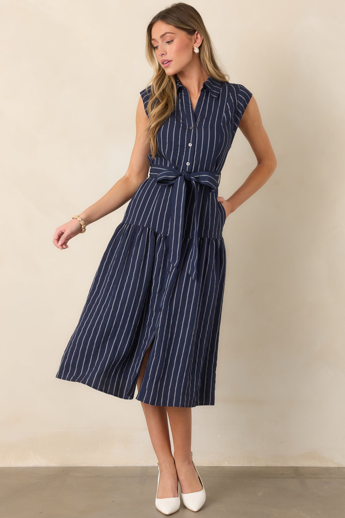 Sleeveless striped midi dress showcasing its defined waist, drop-waist seam, and softly flowing full skirt.