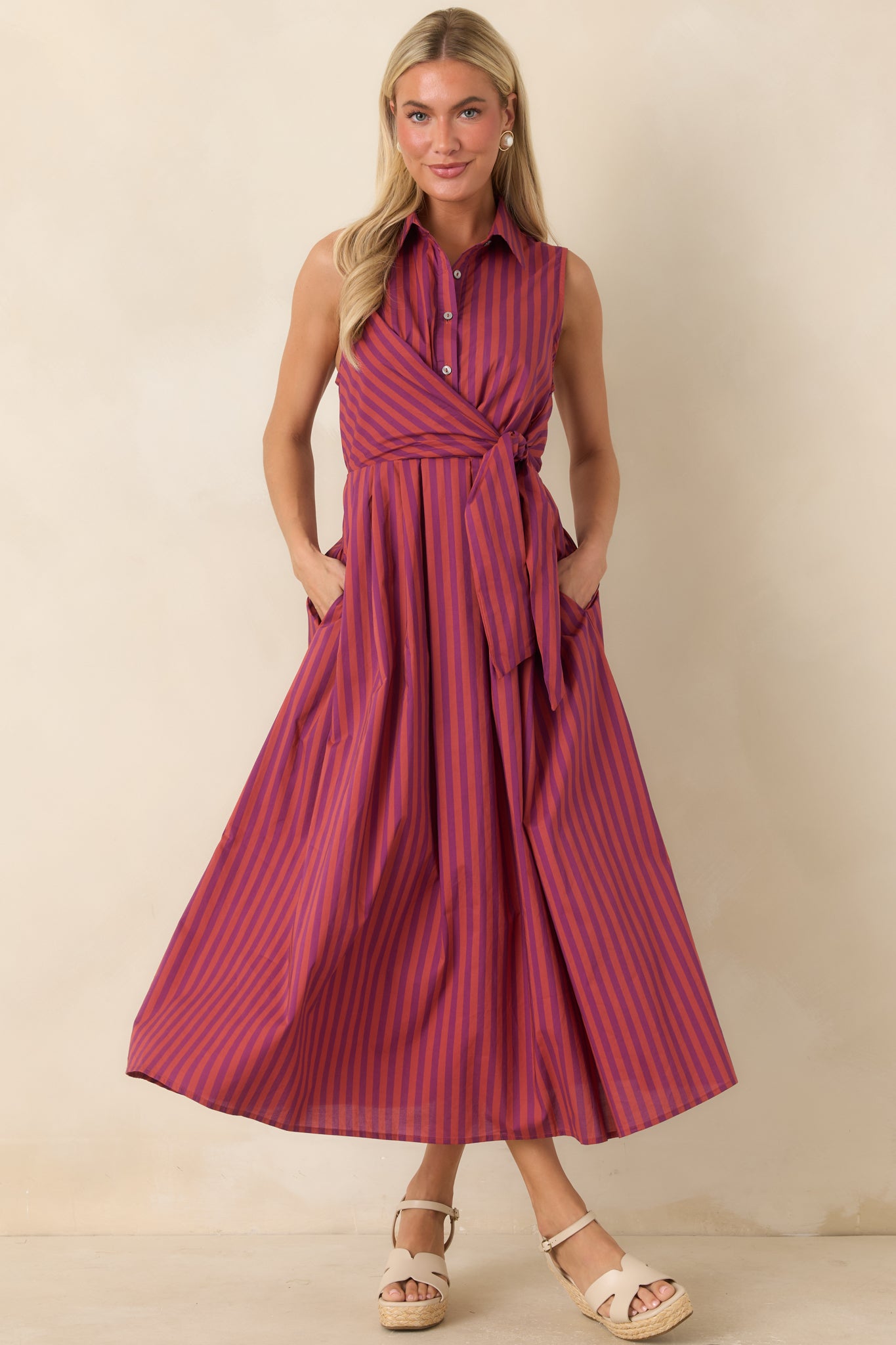 Sleeveless shirtdress with bold vertical stripes, a defined tie front waist, elasticized back waist, and practical side pockets.