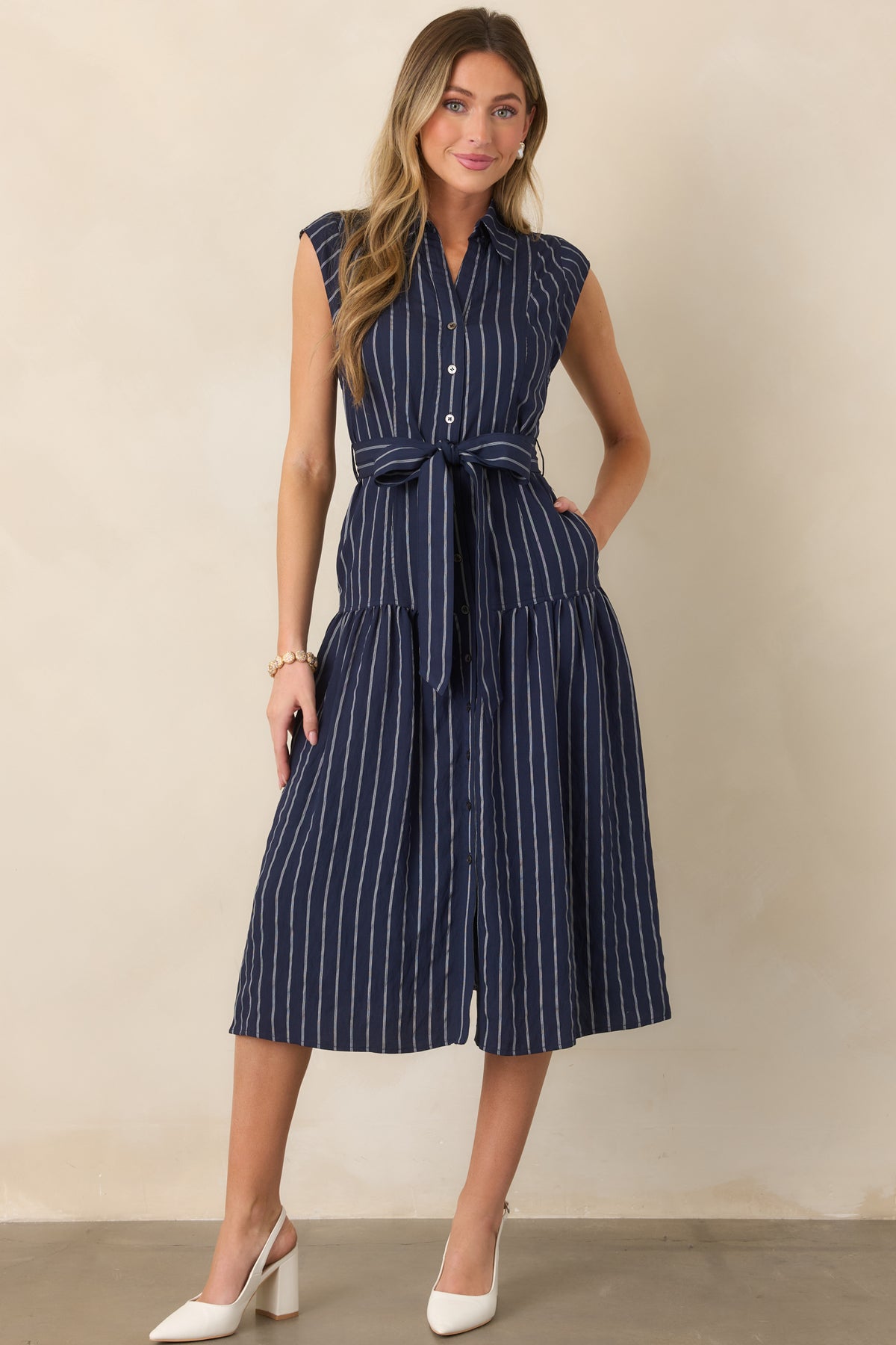 Sleeveless woven midi dress highlighting its vertical stripes, removable self-tie belt, button-front design, and flowing full skirt.