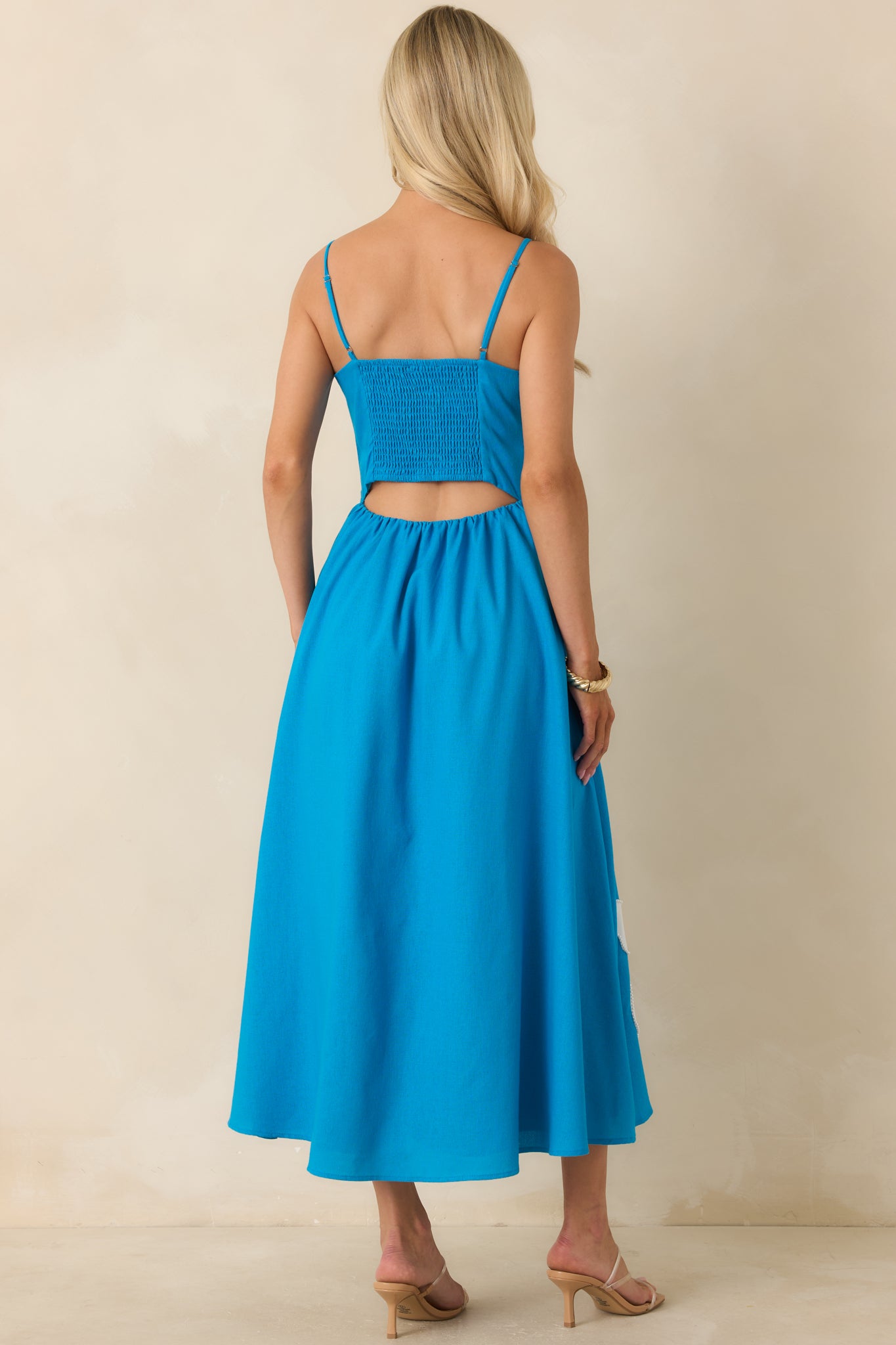 Back view of the midi dress highlighting the smocked back panel, subtle cutout detail, adjustable straps, and flowing skirt.