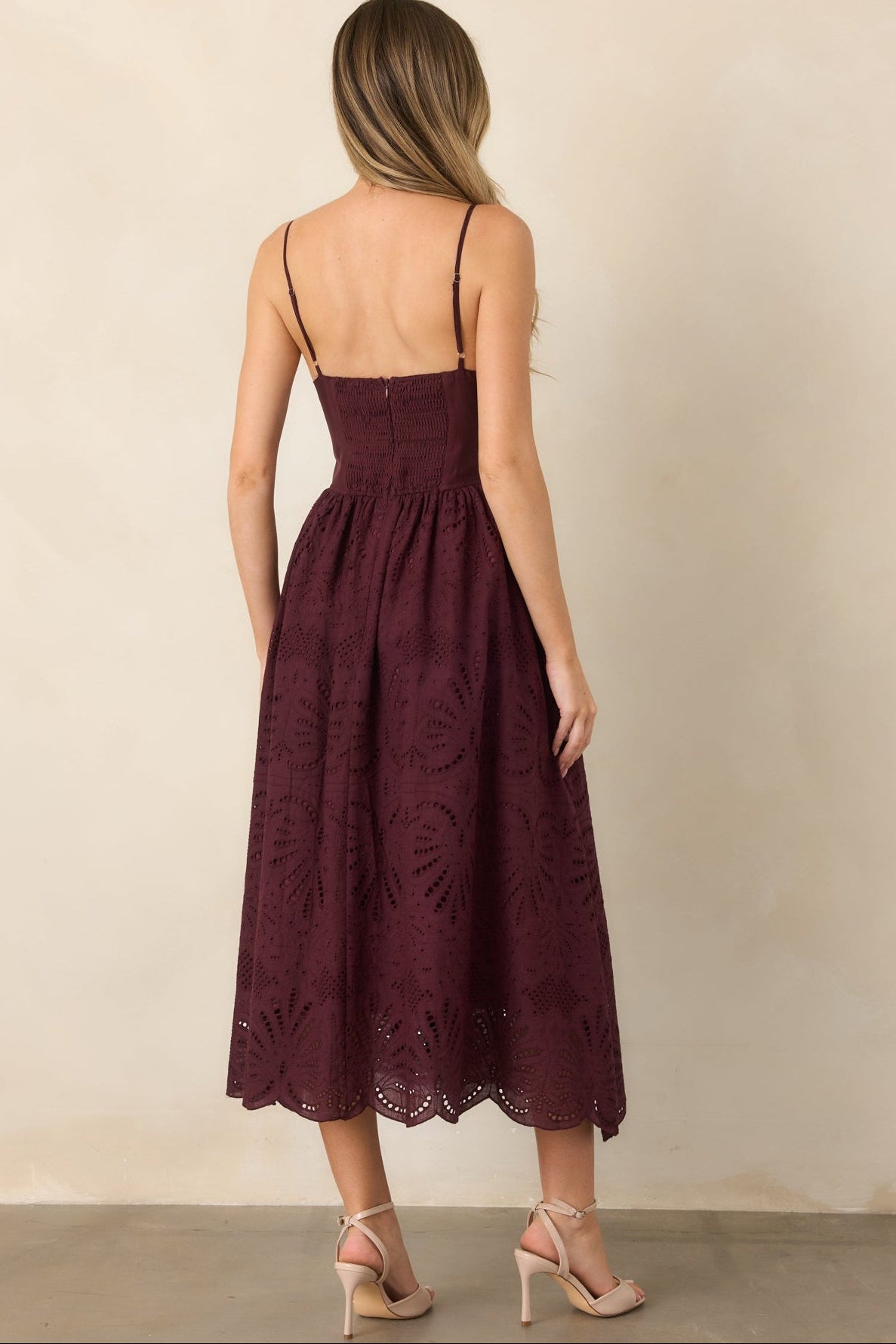 Rear view of the eyelet dress showcasing the smocked back panel, adjustable straps, concealed zipper, gathered skirt, and scalloped hem.