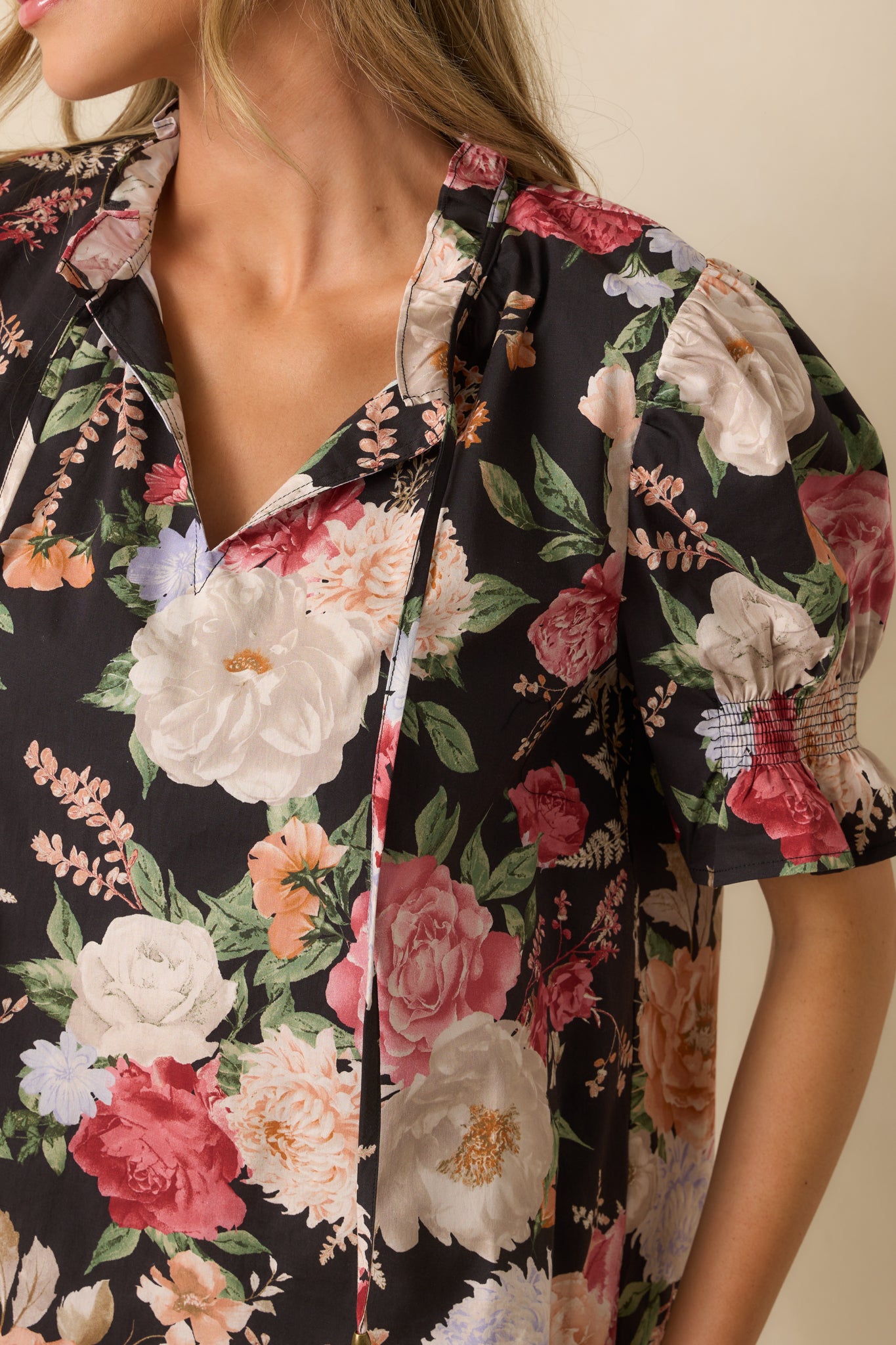 Detailed view of the smocked ruffle cuffs, puff sleeves, and split v-neckline with tassels.