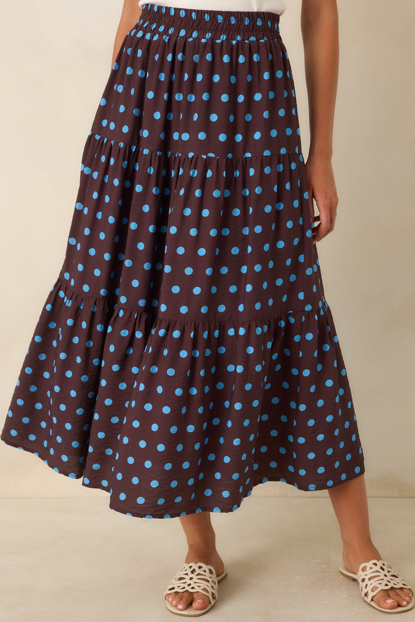 Close view of the smocked elastic waistband and gathered tiered panels on the brown polka dot skirt.