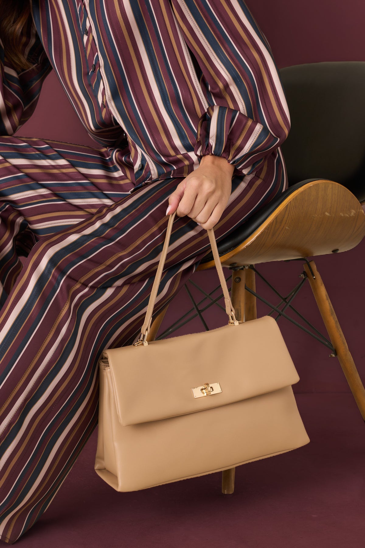 Smooth beige leather handbag with a twist-lock closure and three spacious compartments.