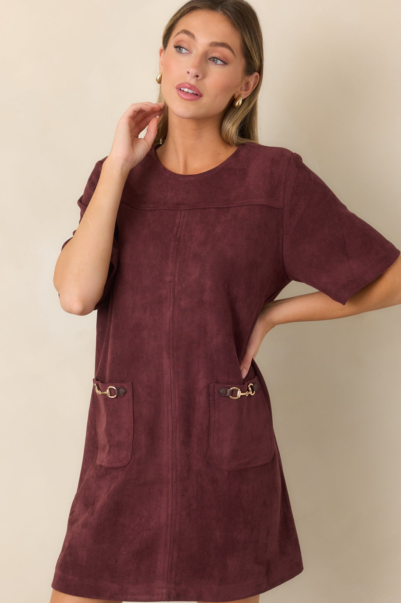 Close view of the mini dress emphasizing its smooth faux suede finish, equestrian-inspired hardware, and structured pocket detailing.