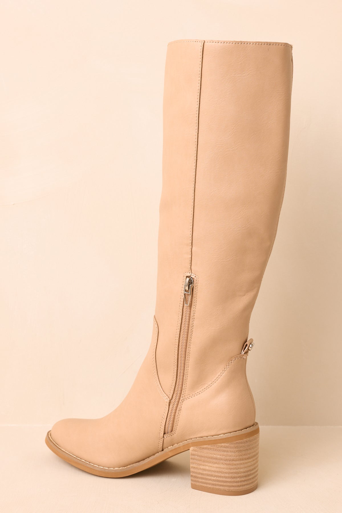 Neutral knee-high boots highlighting the softly rounded almond toe, smooth shaft, and structured stacked heel.