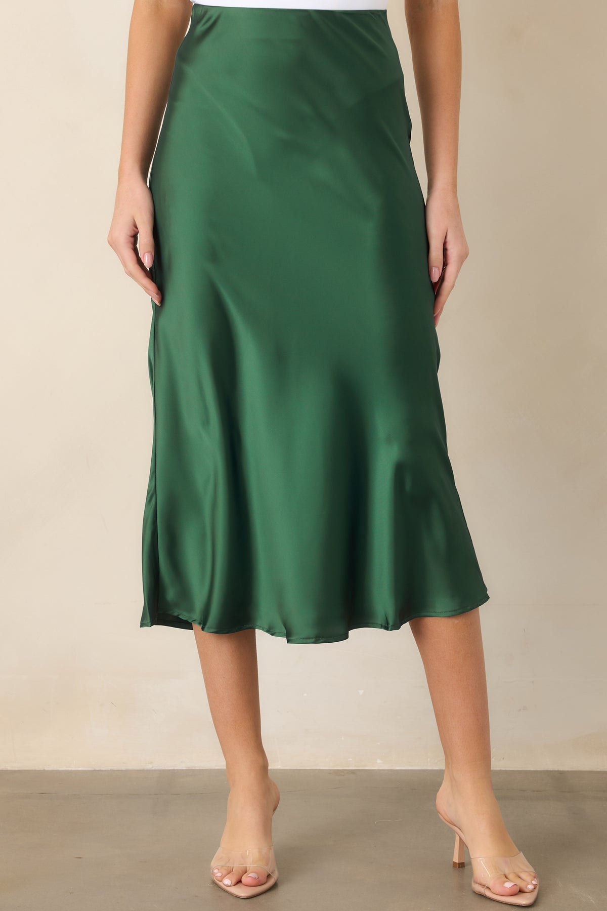 Smooth satin midi skirt highlighting its clean elastic waistband, streamlined fit through the hips, and fluid flare.