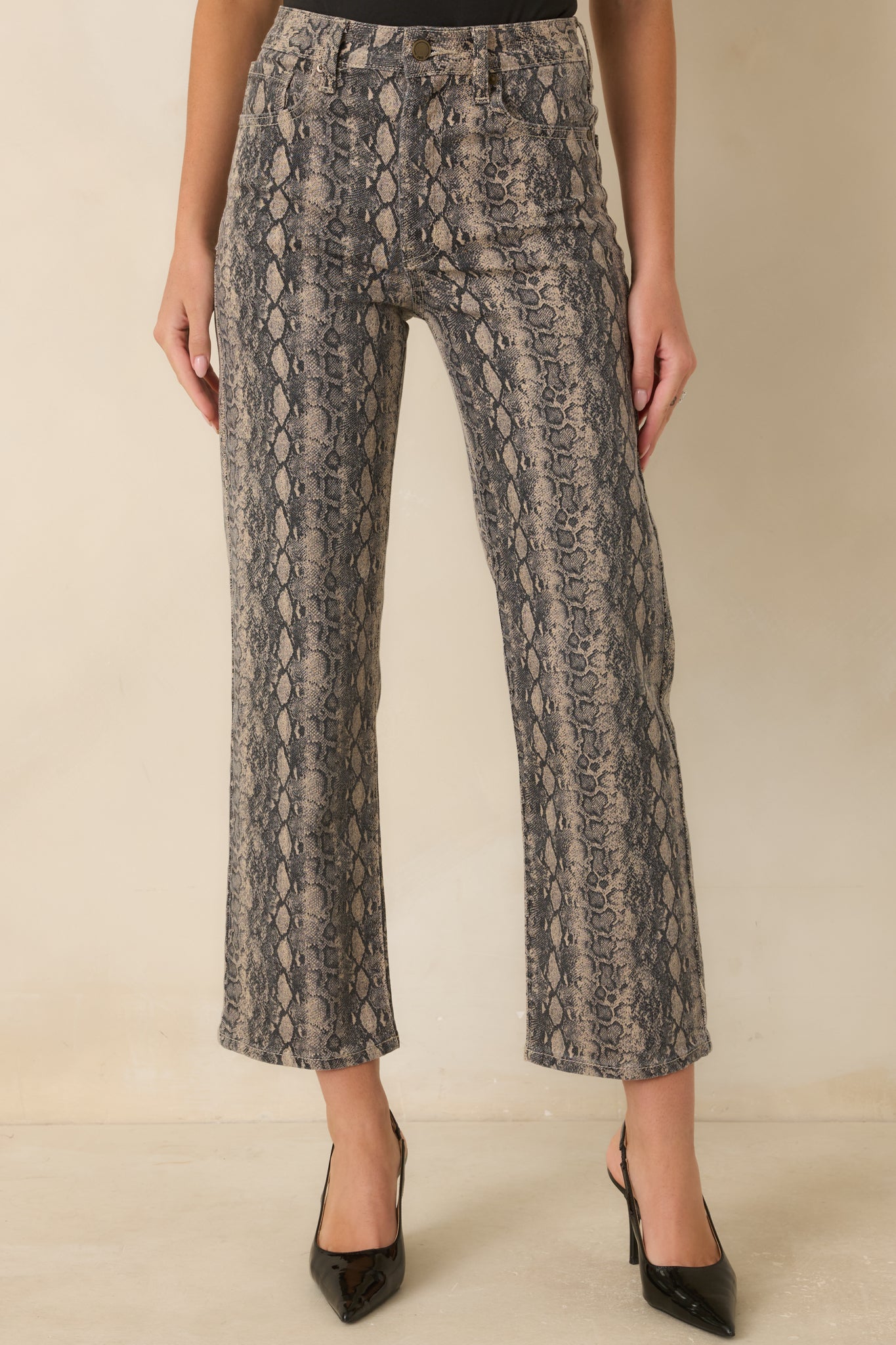 Close view of snakeskin jeans highlighting the high-rise waistband, belt loops, and front pocket details.