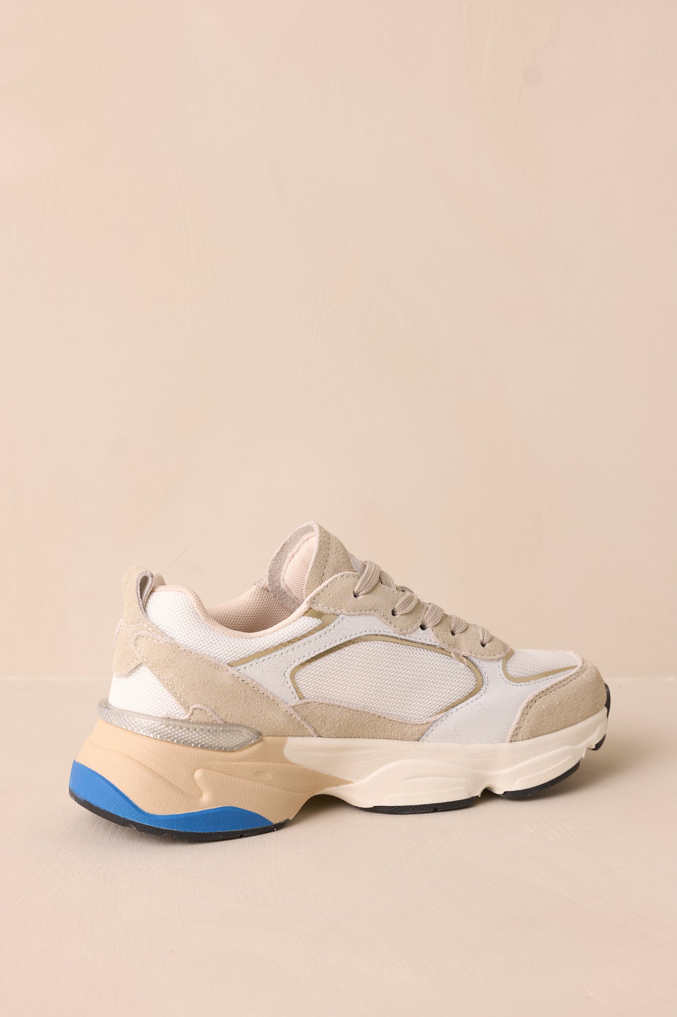 Another angled back view highlighting the blue accent along the thick beige sole of the sneaker.