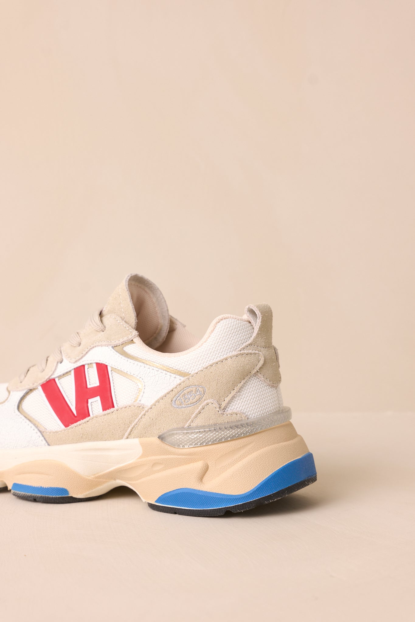 Back view showing the heel, thick beige sole with blue accents, and grey upper of the sneakers.