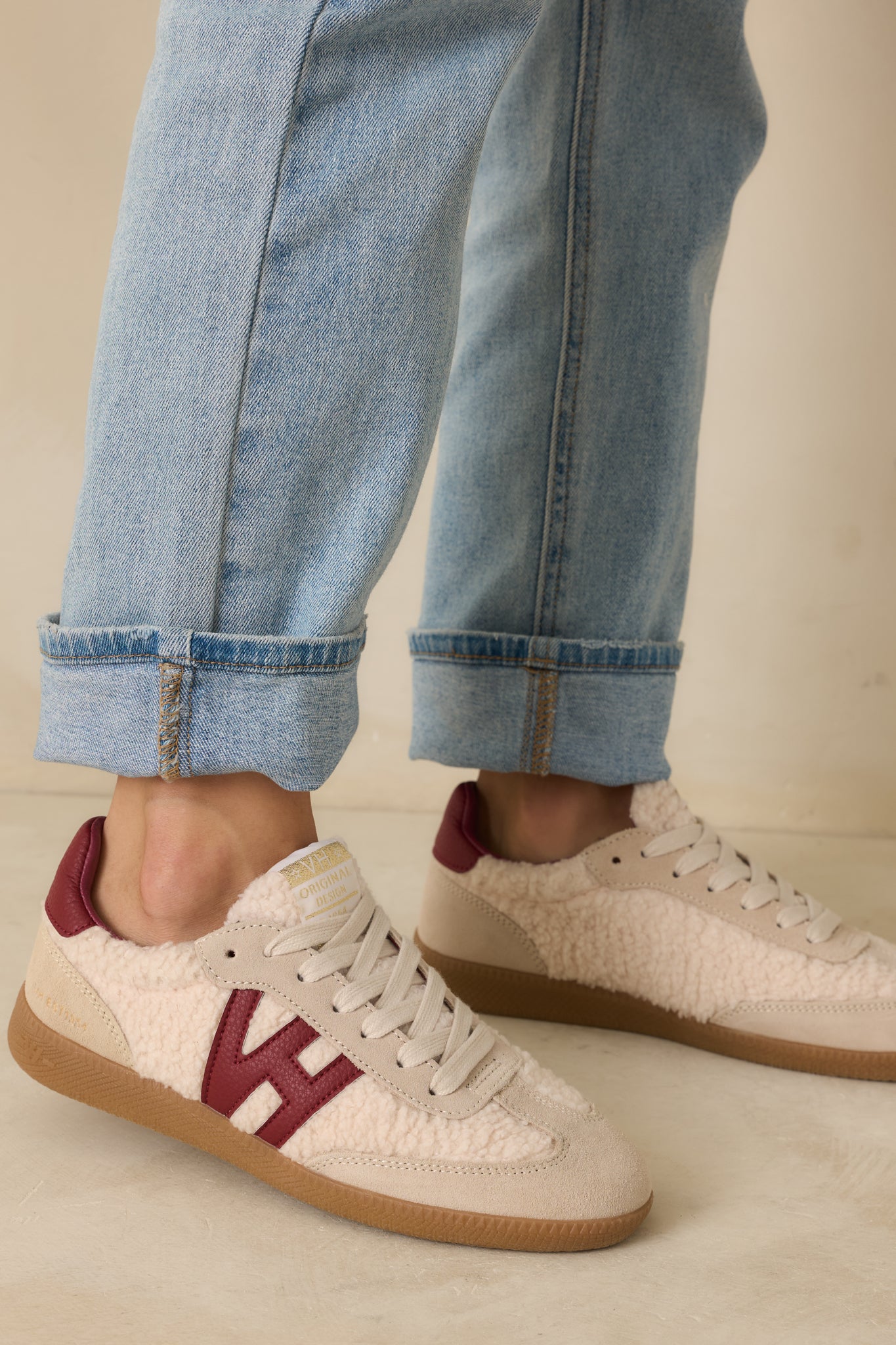 Detailed view of gold logo on tongue, textured sherpa panels, and rich burgundy accents.