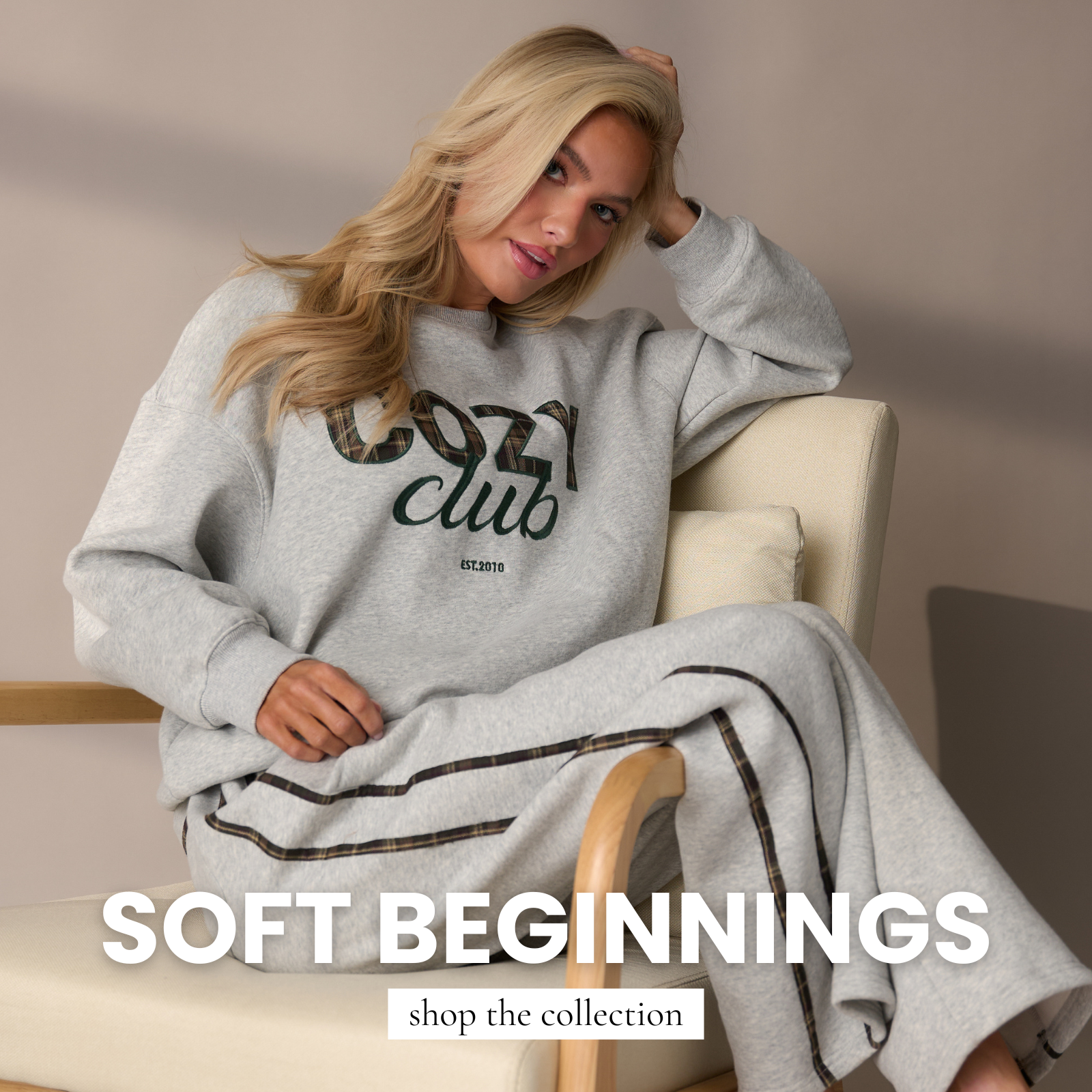 Woman wearing a relaxed gray sweatshirt and matching wide-leg lounge pants, styled casually while seated in a neutral-toned chair.