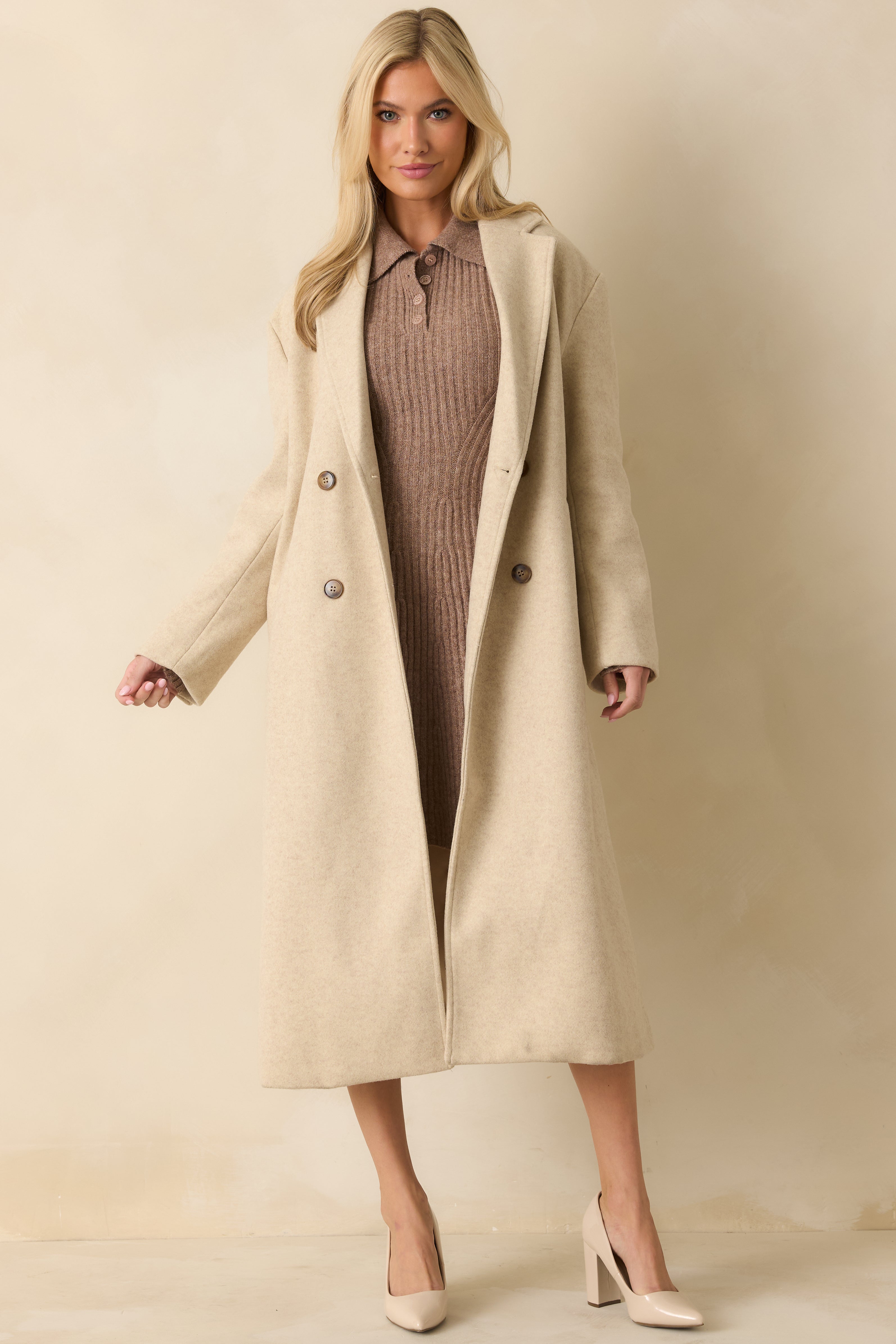 Elegant longline coat in soft beige, featuring a structured double-breasted front and functional side pockets.