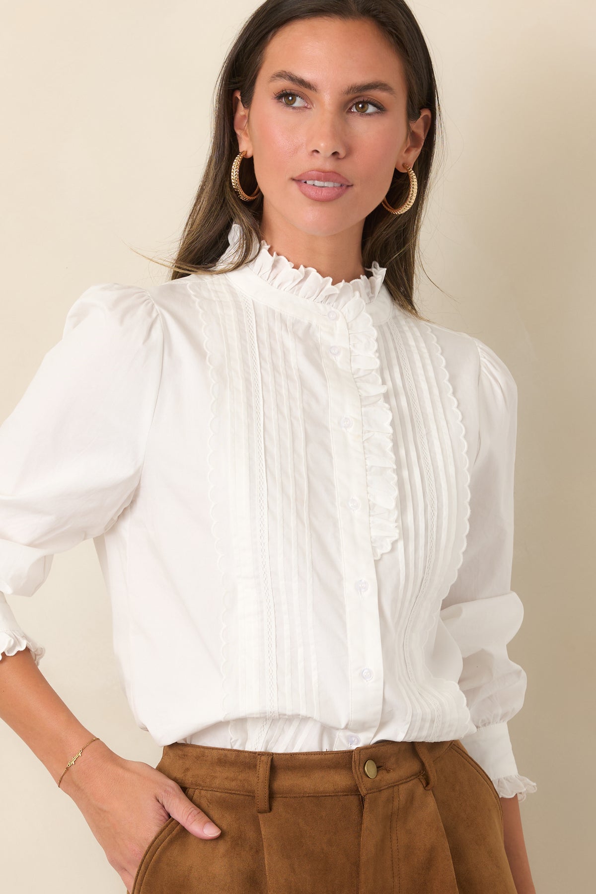 Soft ivory blouse showcasing the classic button placket and ruffle-trimmed shoulders.