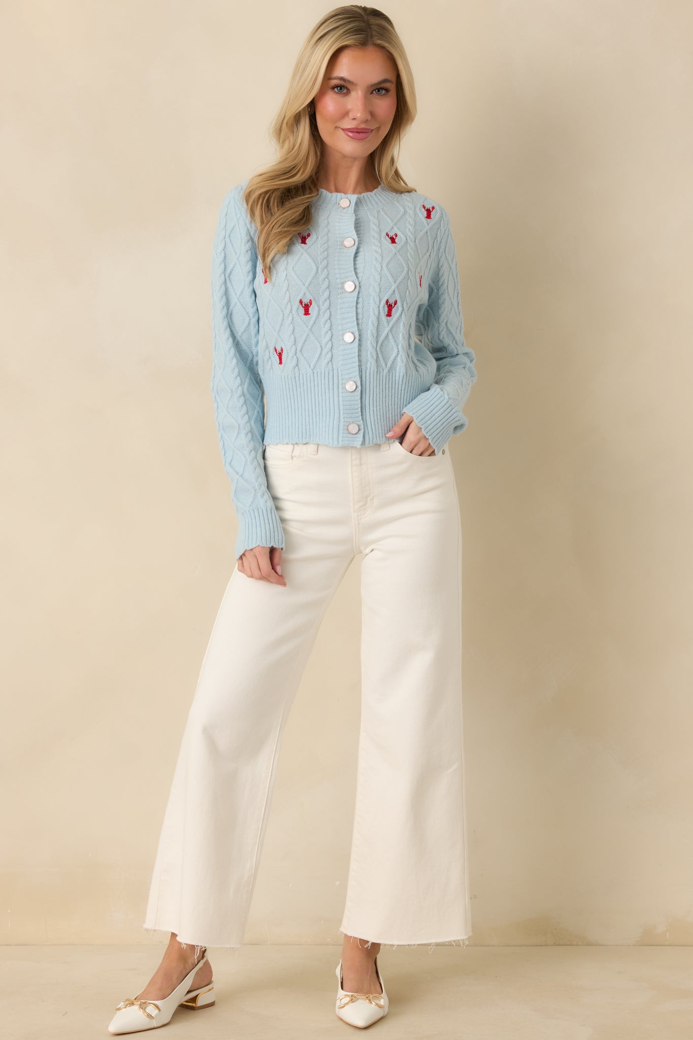 Front view of soft knit cardigan, gold-trimmed pearlescent buttons accenting long sleeves.