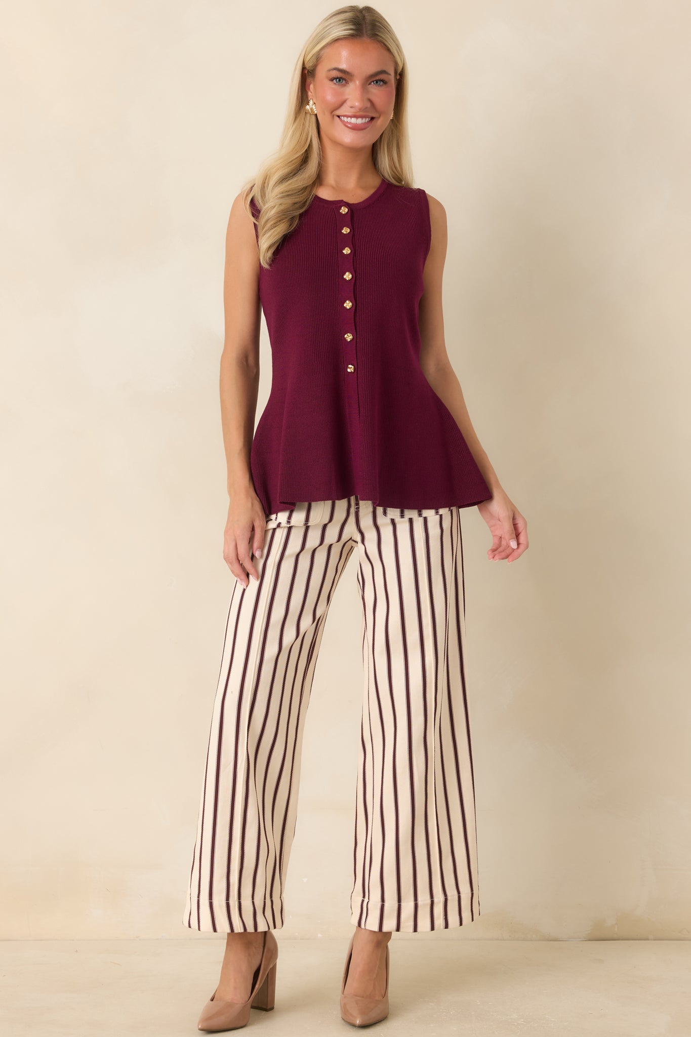 Soft knit sleeveless top featuring gold-tone button accents and a gently flared hem for a polished look.