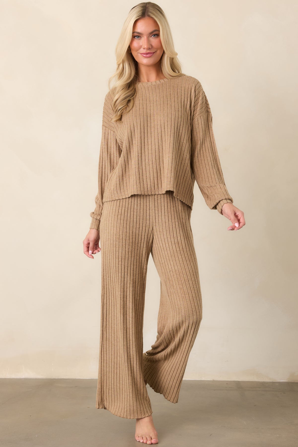 Soft light beige pants with a high-rise smocked waistband, subtle ribbed texture, and relaxed wide legs.
