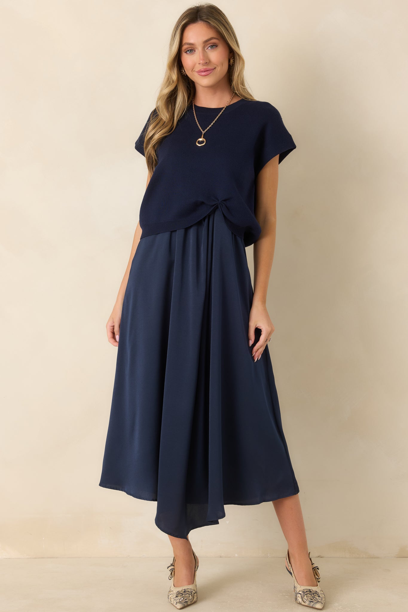 Soft navy knit top featuring a relaxed fit, cap sleeves, a ribbed neckline, and a distinctive cinched front hem.