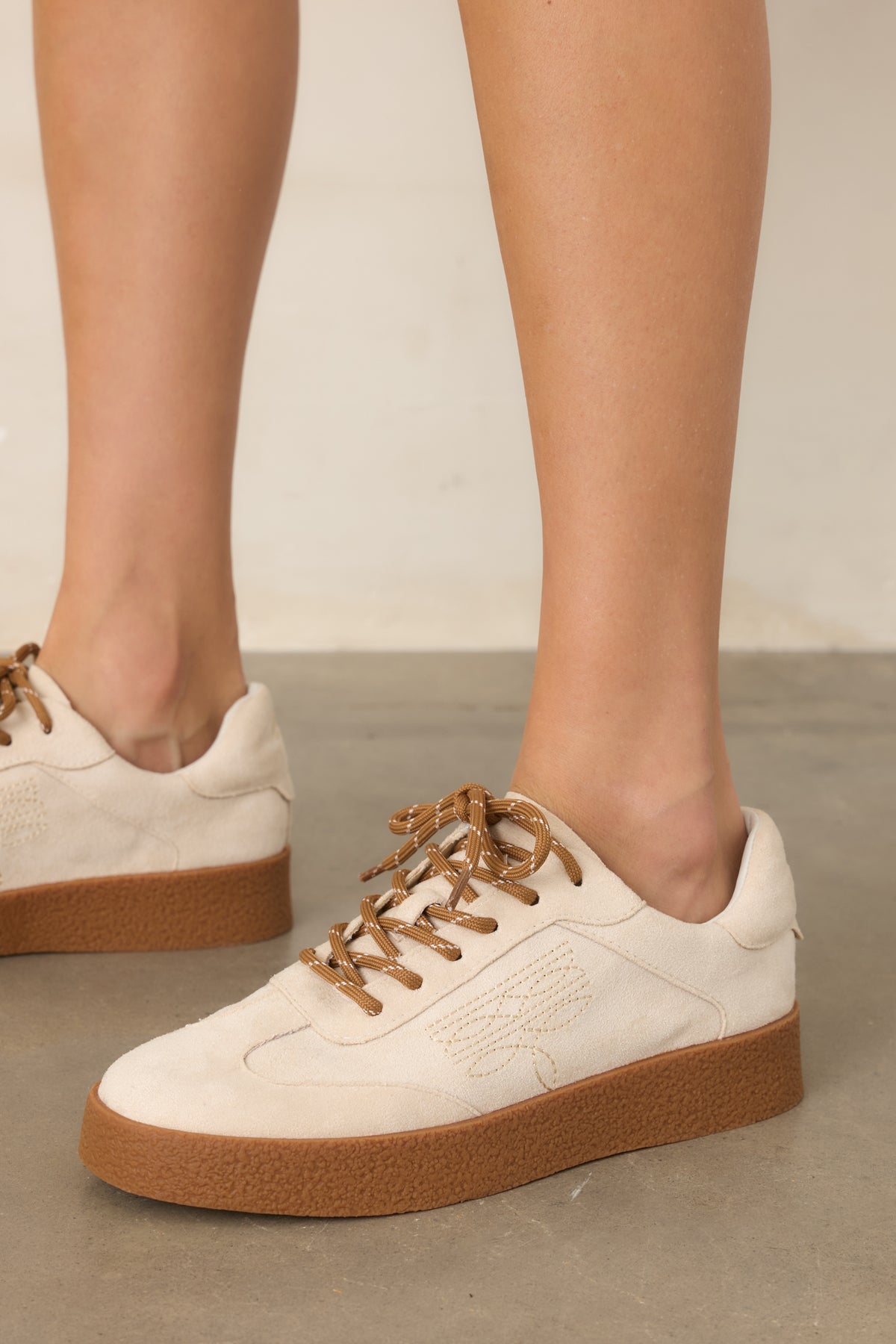 Soft neutral faux suede sneakers featuring tonal stitching and a classic rounded toe.