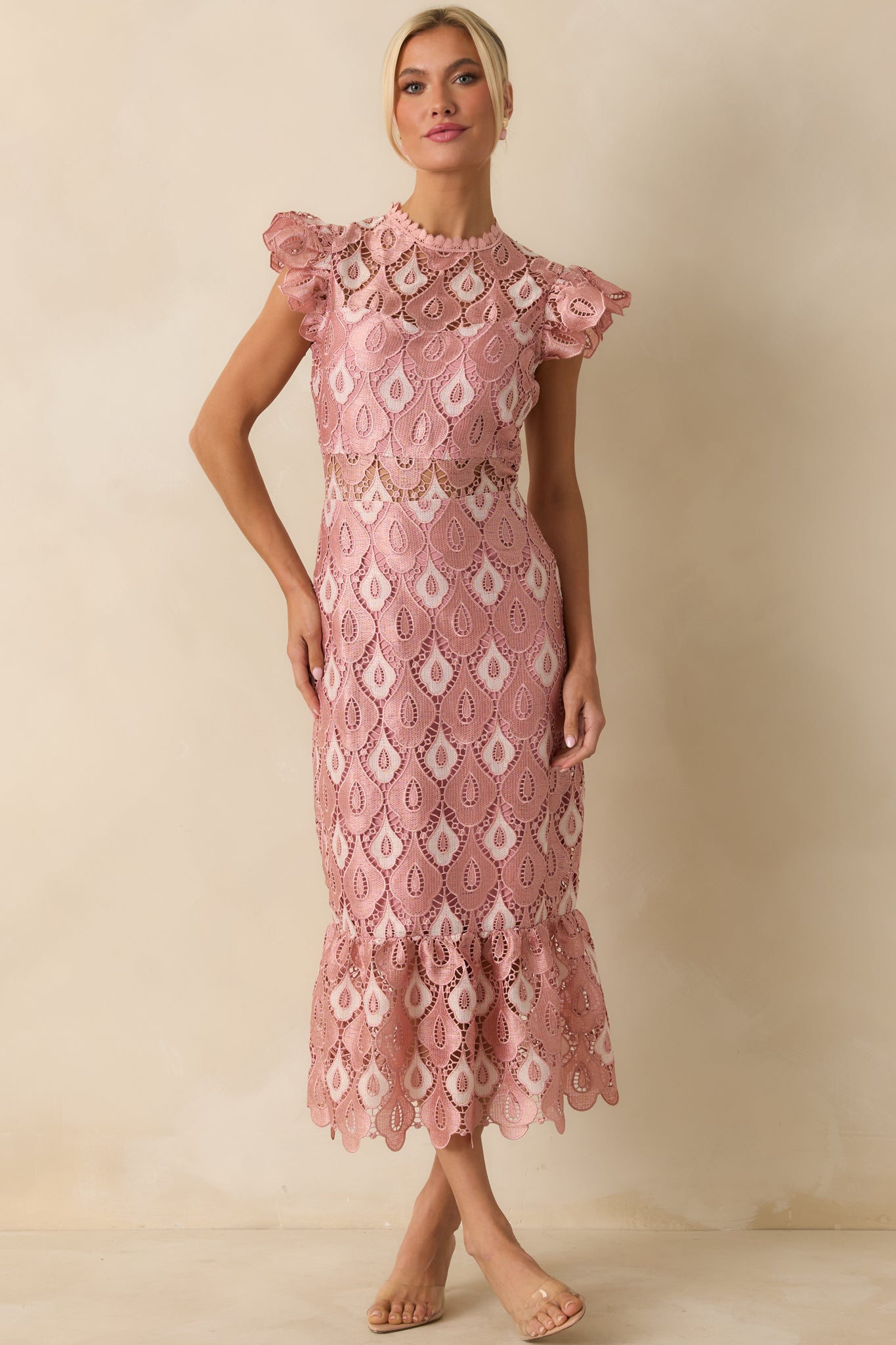 The maxi dress shows its soft pink lace fabric with a fitted bodice, short sleeves, and flounced hem.