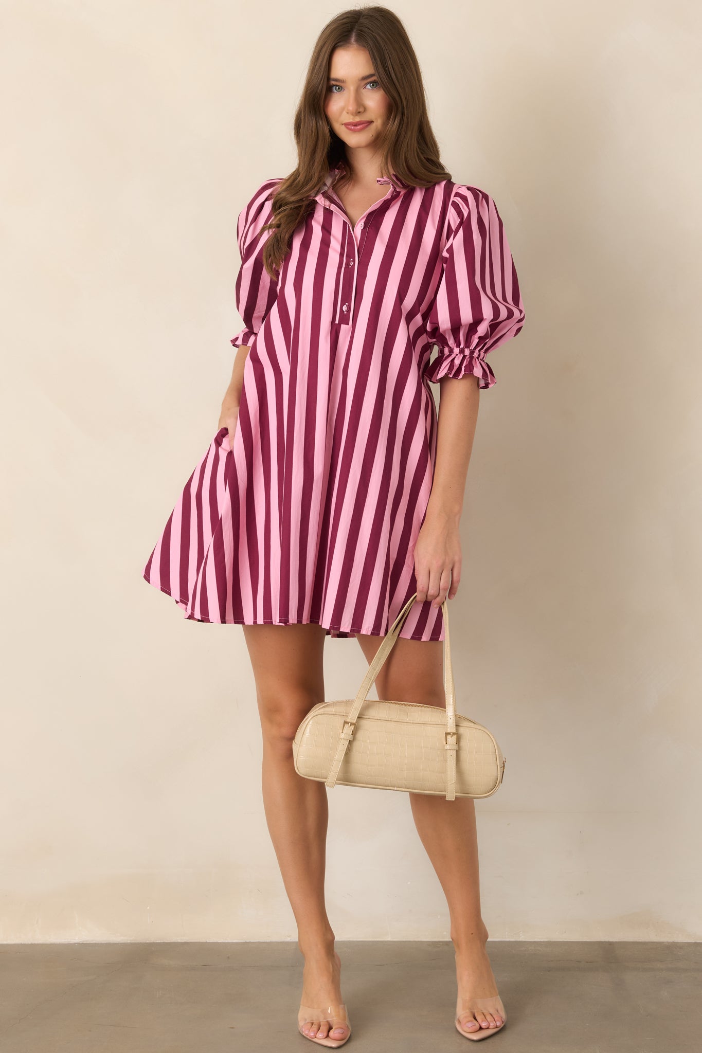 Soft pink and rich wine striped cotton mini dress featuring a ruffled mock collar, partial button-front placket, voluminous three-quarter puff sleeves, and a relaxed shift silhouette.