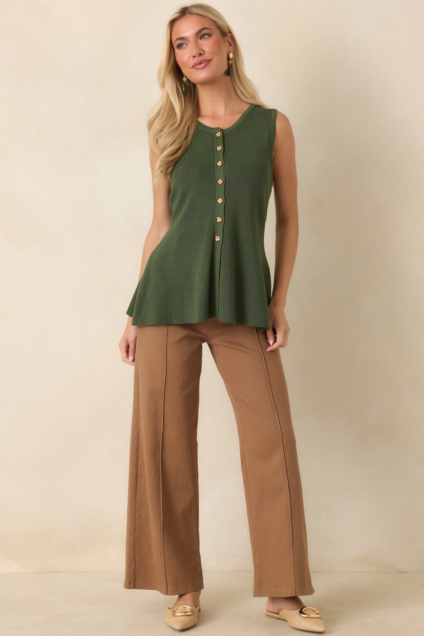 Soft stretch knit top with a smooth finish, gold-tone button details, and a polished peplum silhouette.