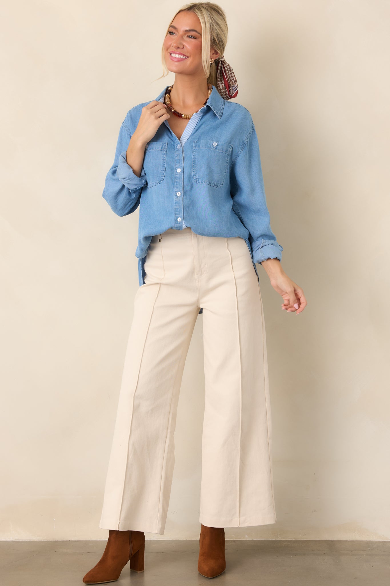 Soft-washed denim top with a classic collar, full button-front closure, dual chest patch pockets, relaxed fit, and curved high-low hem.