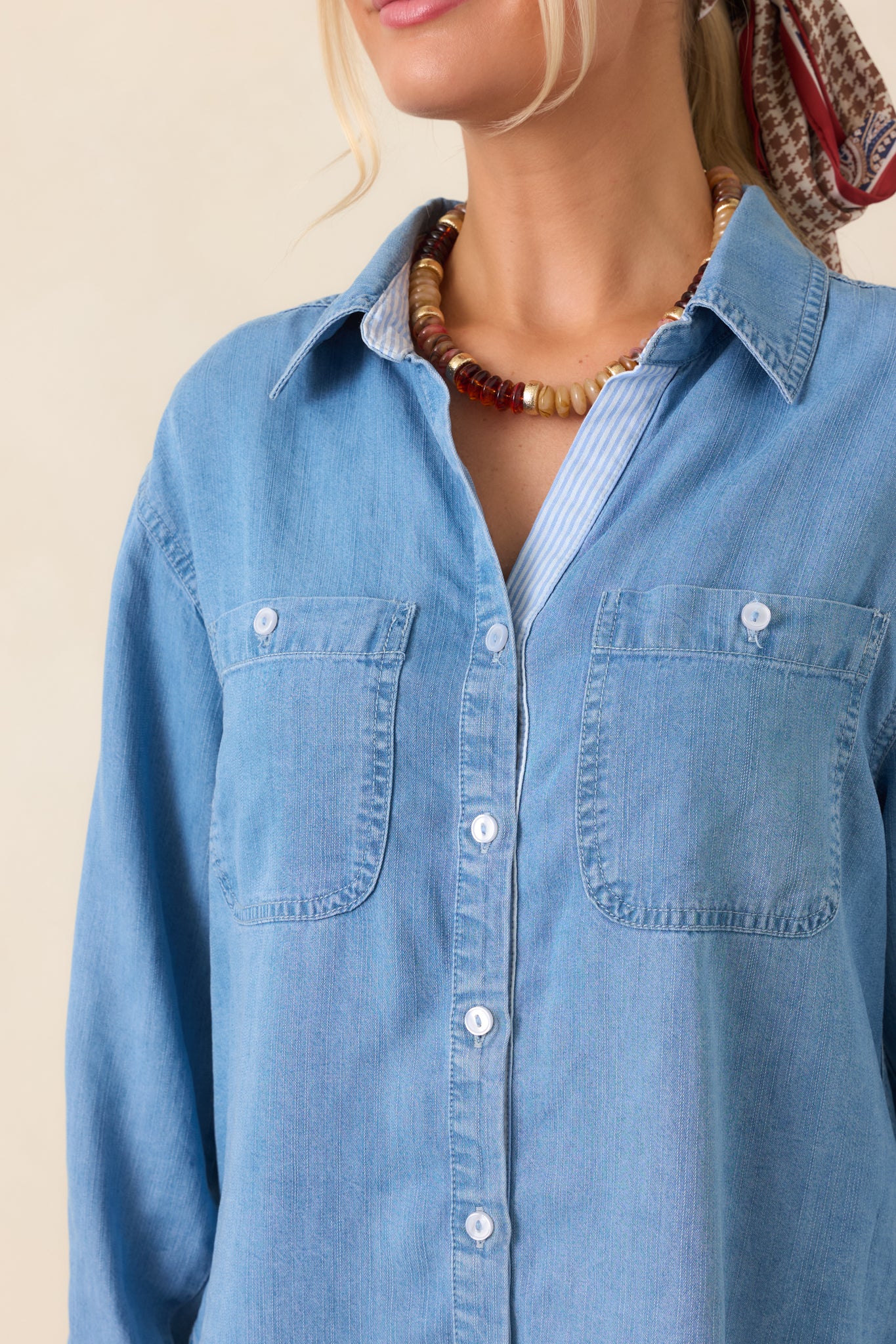 Close-up of the soft-washed denim top highlighting the collar, button-front closure, dual chest pockets, and subtle faded texture.
