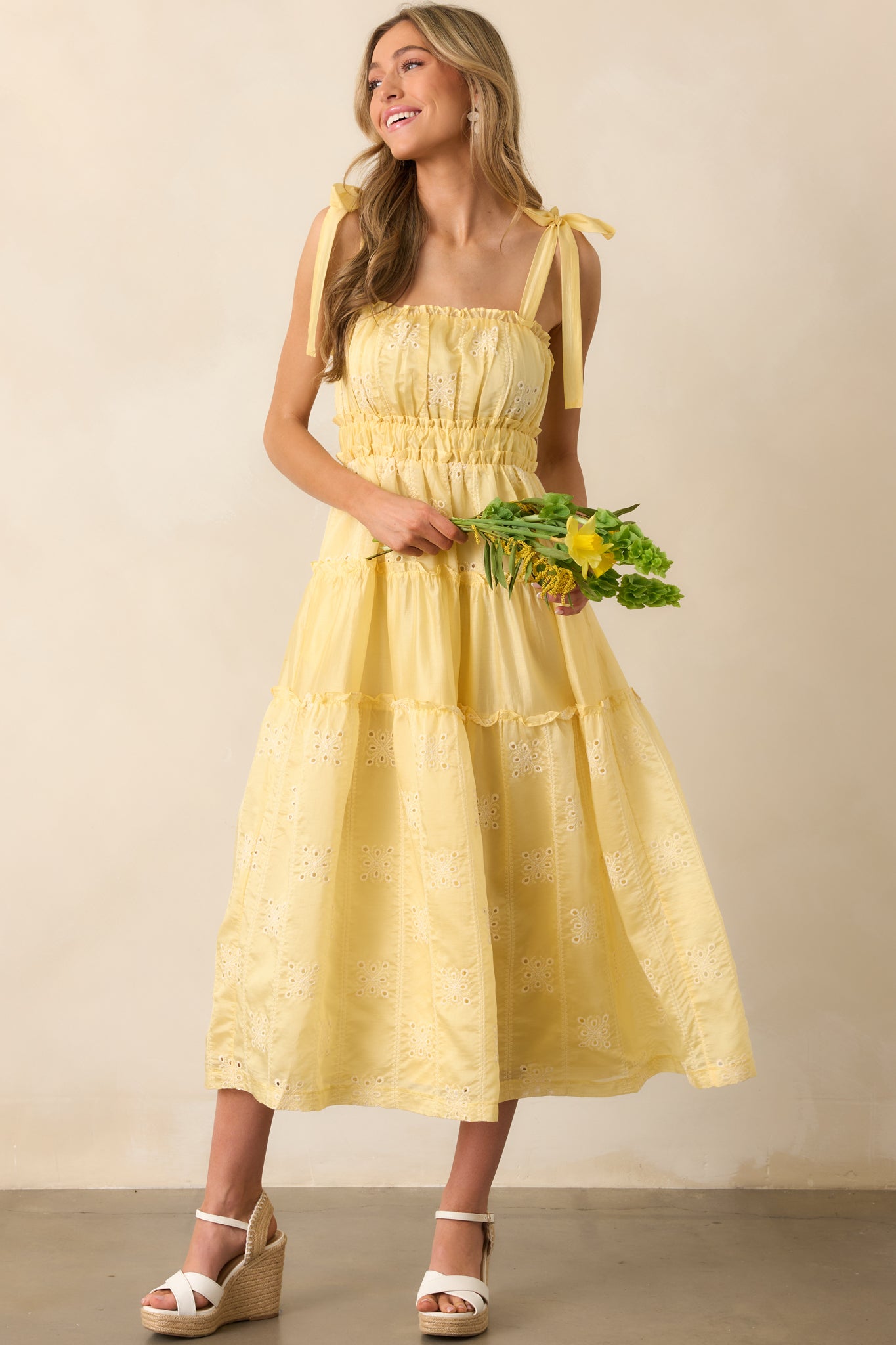 A soft yellow midi dress with a flattering elastic waist and elegant ruffle accents throughout.