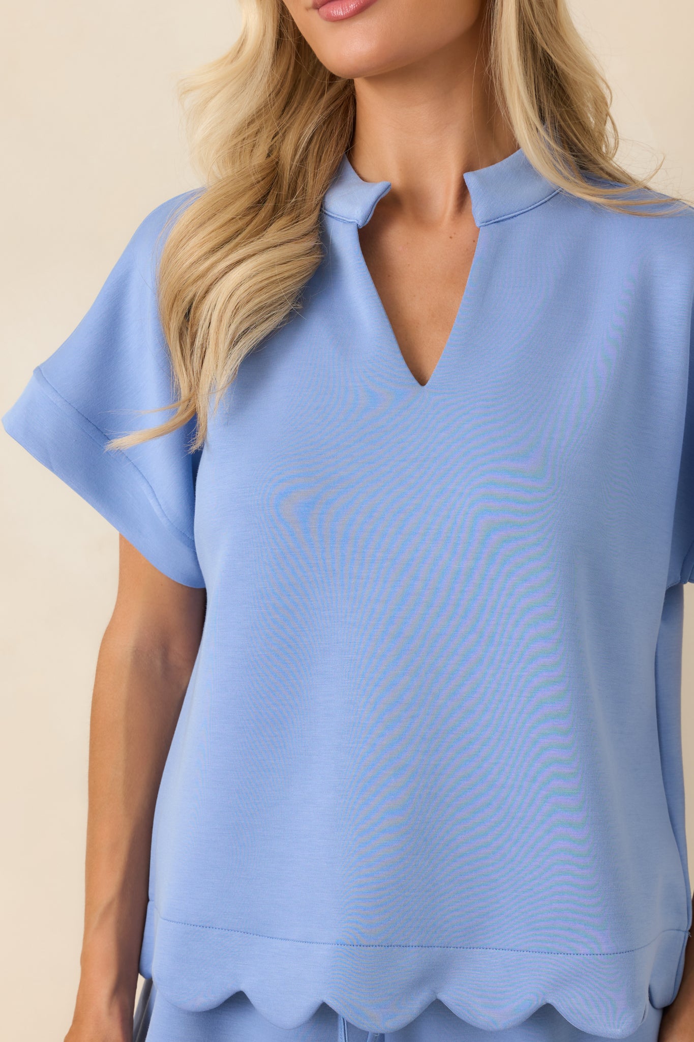 Close-up view of the split neckline, cuffed sleeve detail, and scalloped hem craftsmanship.