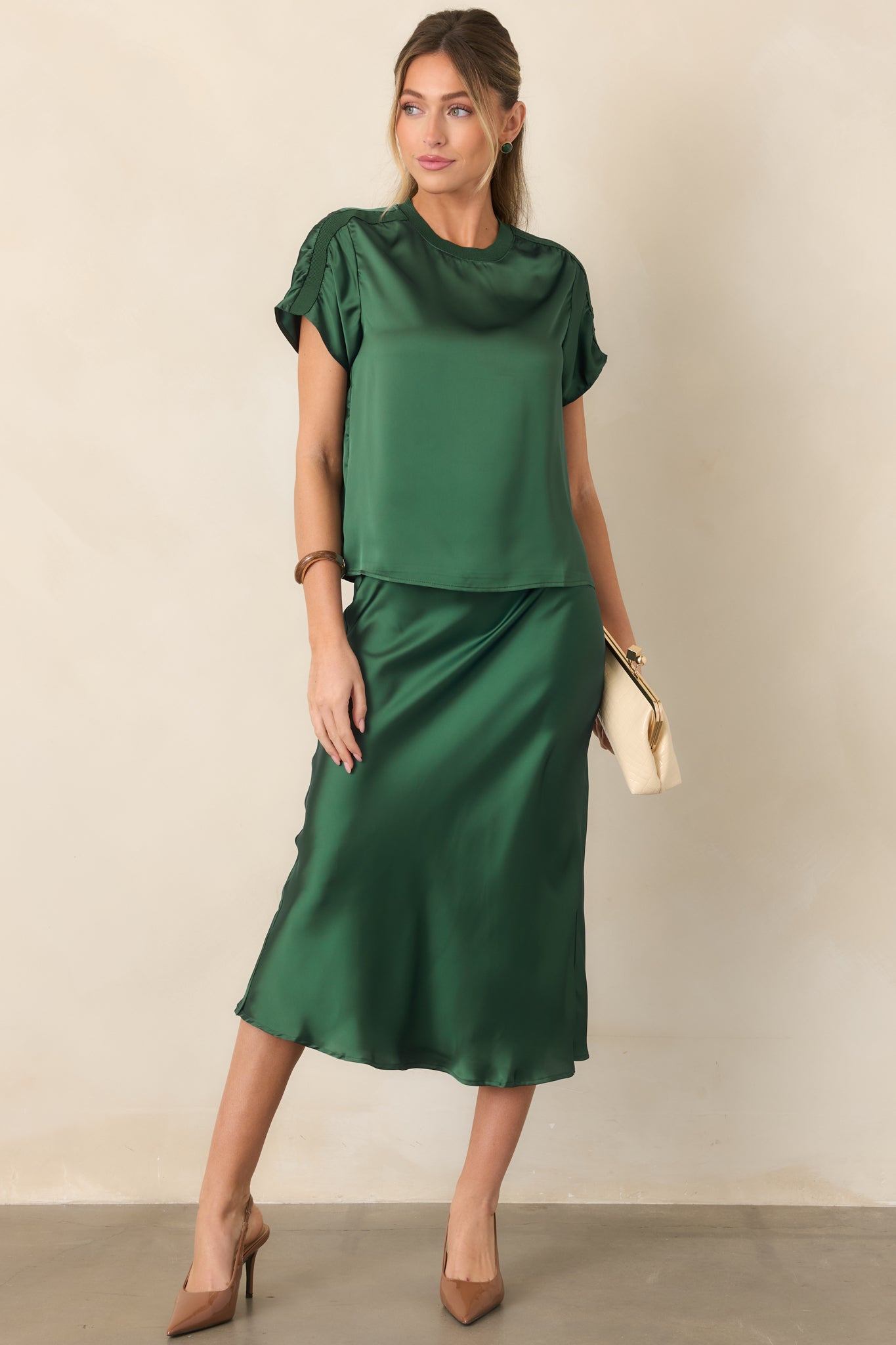 Sporty-inspired satin top showcasing its rounded neckline, short sleeves, subtle sheen, and contrasting ribbed shoulder trim.