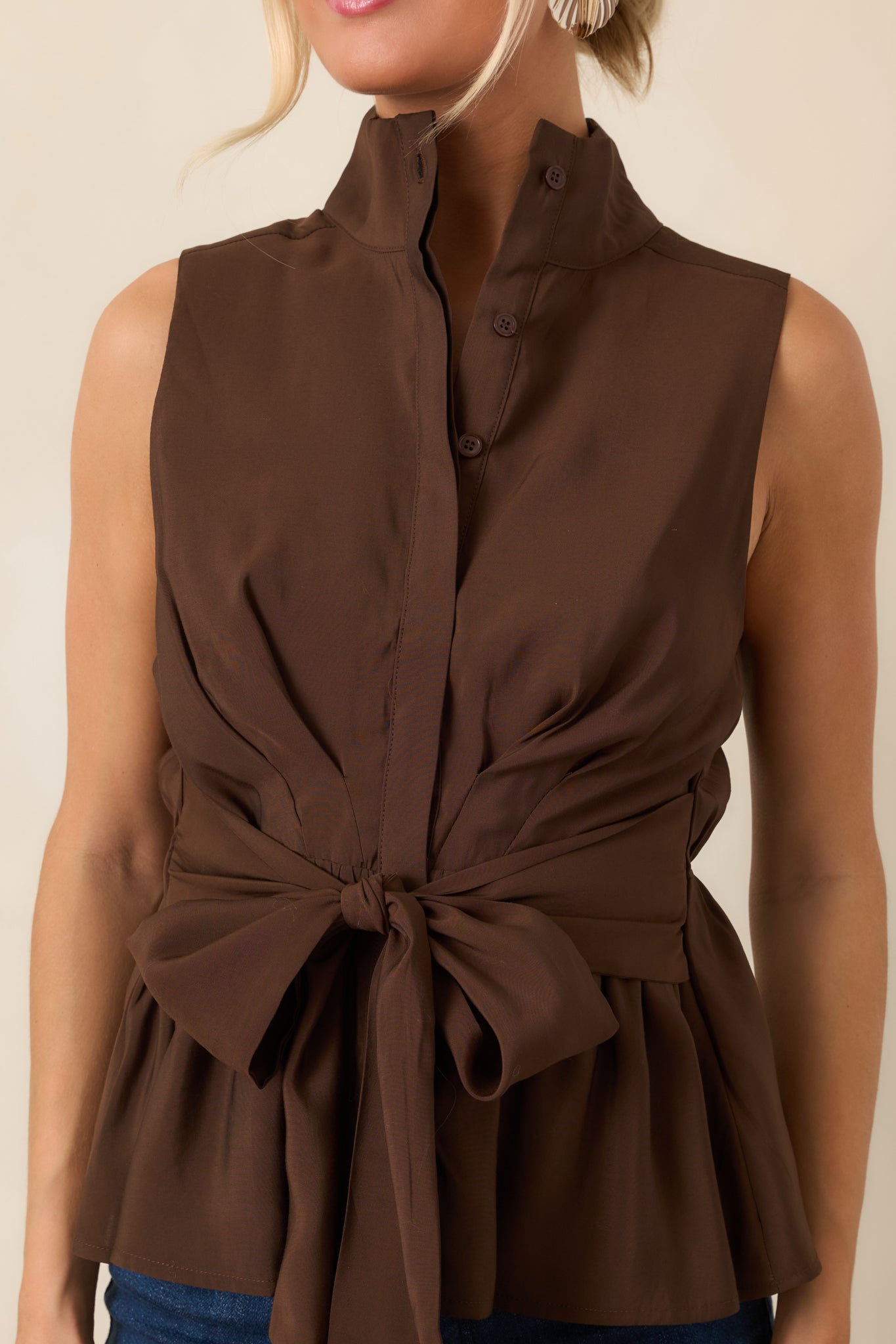 Close-up highlights the stand collar, partial button placket, smooth fabric texture, and oversized front tie detail.