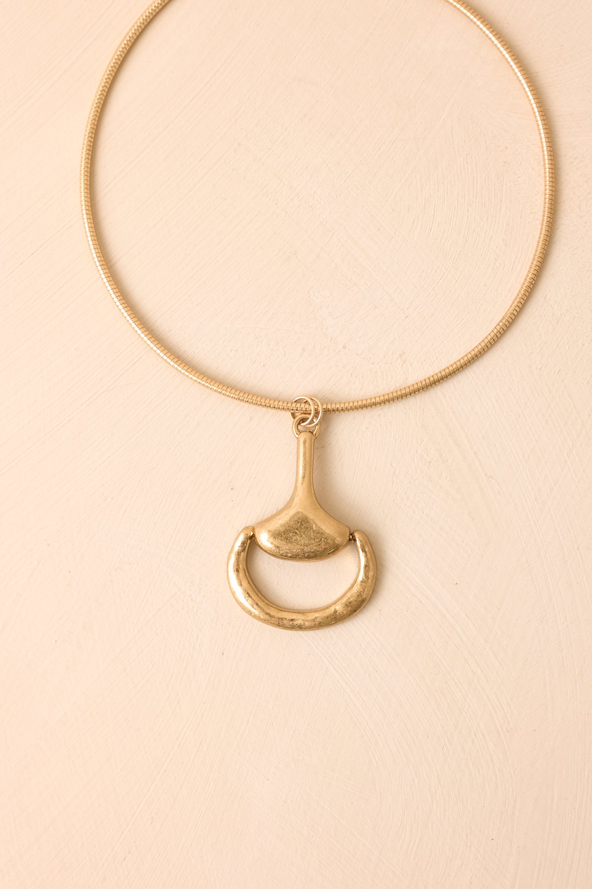 Statement necklace showcasing a standout horsebit-inspired pendant suspended from a sleek snake chain.
