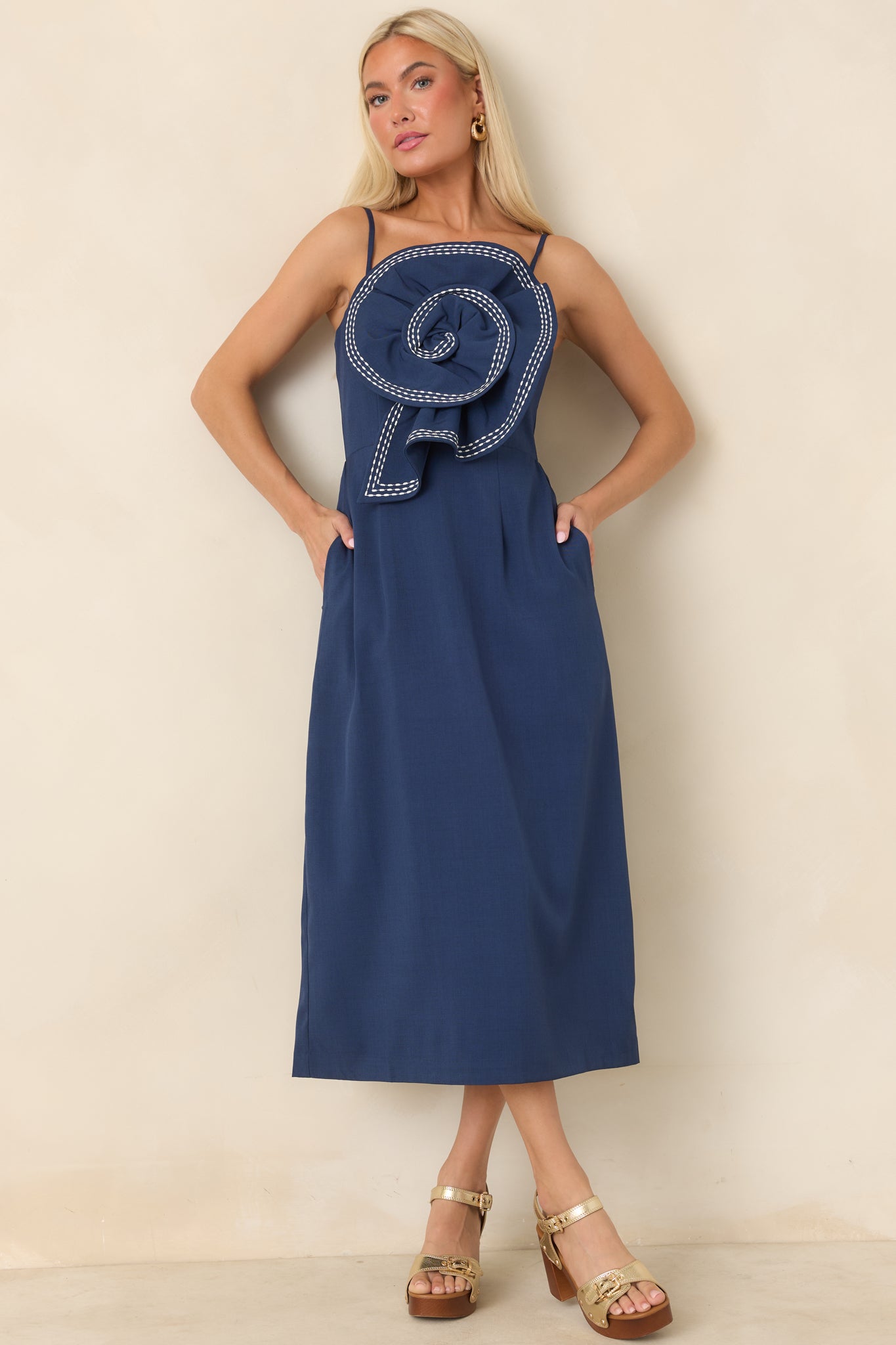 Statement midi dress with contrast white stitching, a softly structured skirt, and a dramatic floral appliqué.