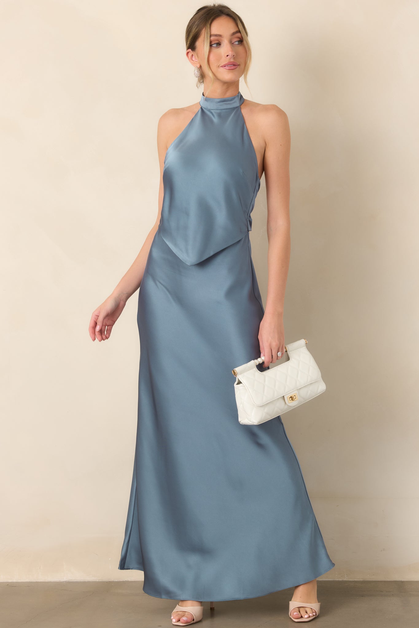 Elegant satin maxi dress with a sleek halter silhouette, defined pointed overlay, and flowing skirt that creates graceful movement.