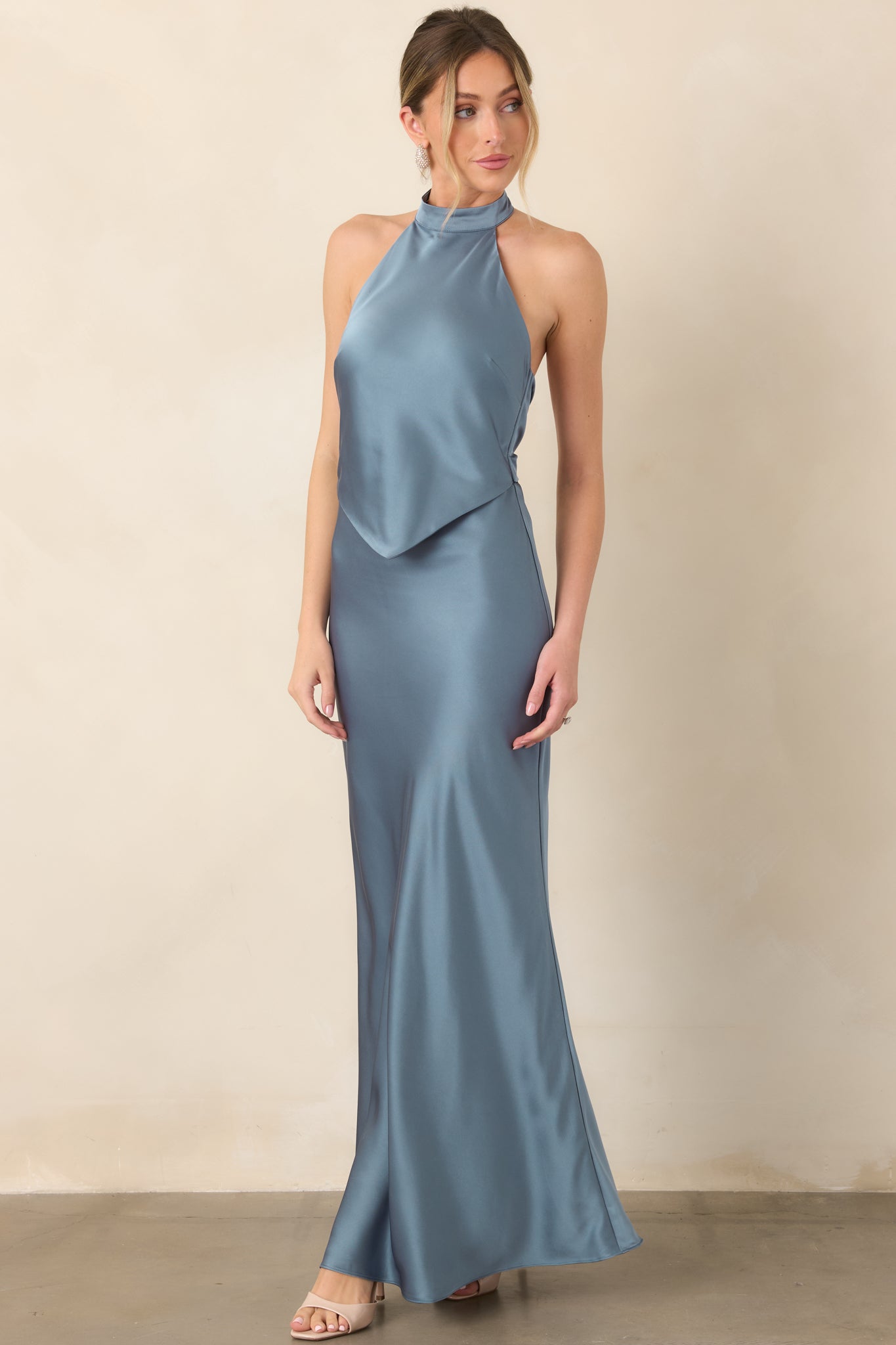 Lustrous steel blue dress showcasing a sculpted halter neckline, layered pointed bodice detail, and gracefully draped maxi skirt.